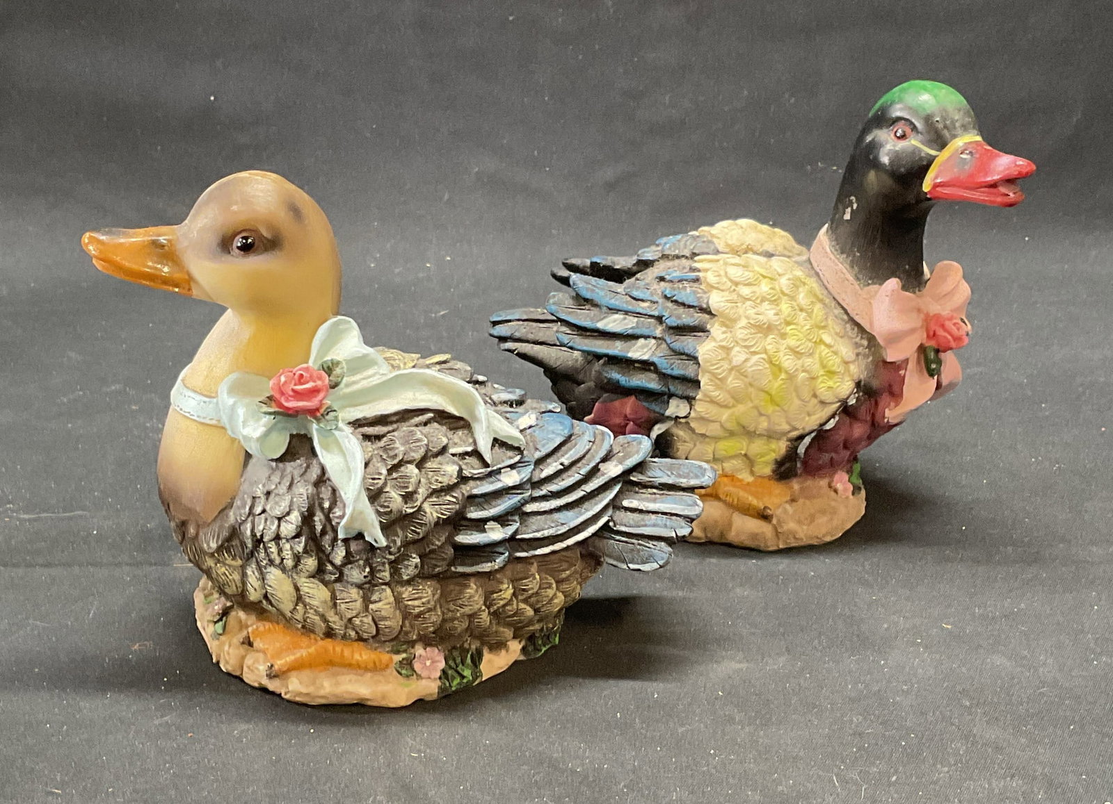 Lot 2 Star Britt Duck Figurals: Lot of 2 Star Brite duck Figurals. Labeled on undersides. Ducks with blue and pink ribbons. Sizes vary slightly, larger approx. 5.5 x 3.25 x 4.75 inches. Composed of composite material. Both pieces ha