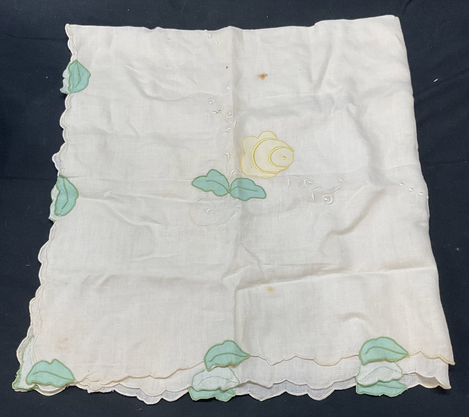 Vintage White Cotton Floral Embroidered Tablecloth: Vintage white cotton tablecloth with yellow and green floral motif and embroidered detail. Measures approx. 34 x 35 inches. Wear to material including blemishes and small holes observed. Tablecloth, w
