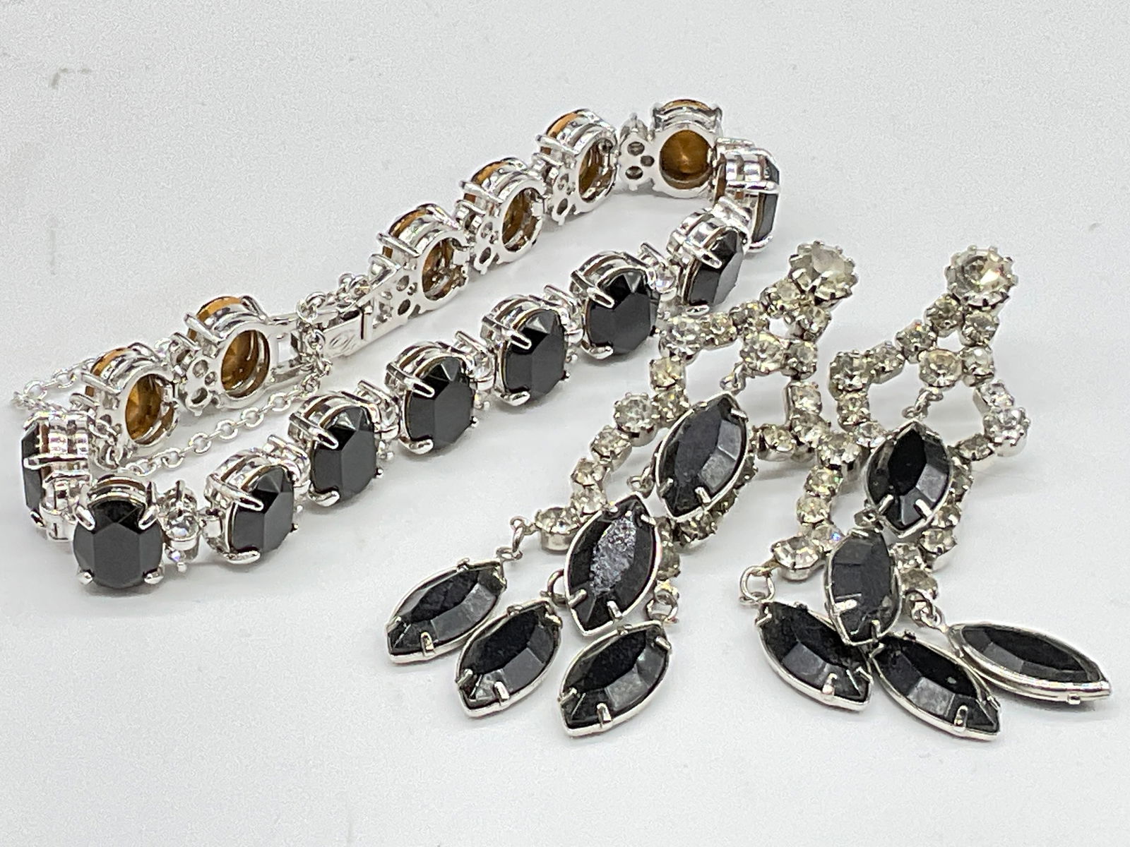 Trademarked D Crystal Bracelet & Crystal Earrings: A black and colorless crystal bracelet and drop earrings. Both are crafted from silver tone metal. The bracelet is trademarked with the letter D on the box clasp closure. The earrings are unbranded. E