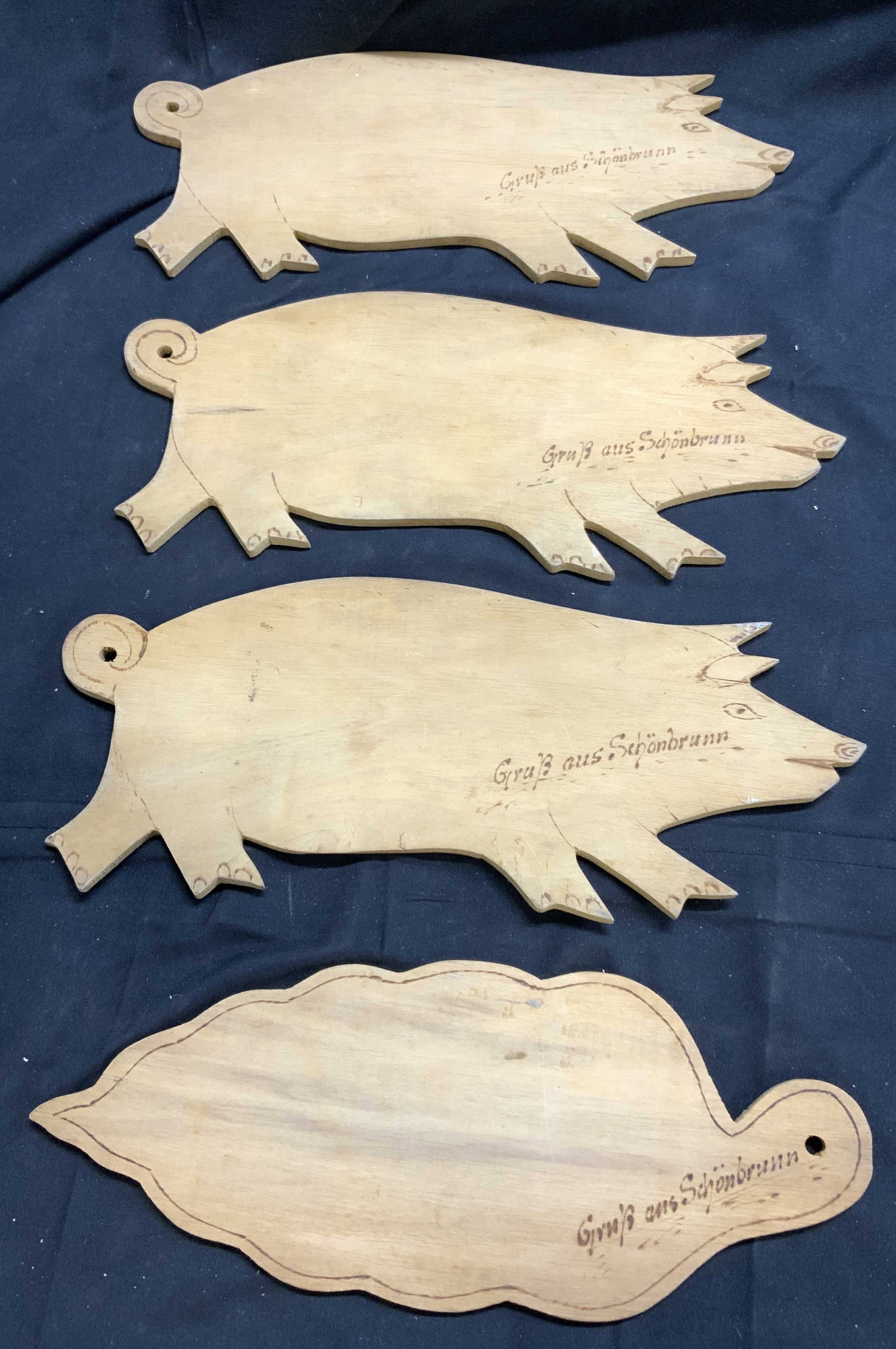 GRUB AUS SCHONBRUNN Lot 4 Wood Board Pigs & Leaf: Each piece reads GRUB AUS SCHONBRUNN. Each piece is tan toned. Lot includes 3 pig & 1 leaf figure. Each appear to be wood board. Pig figures measure approximately 11.75 inches long 5 inches tall. GRUB