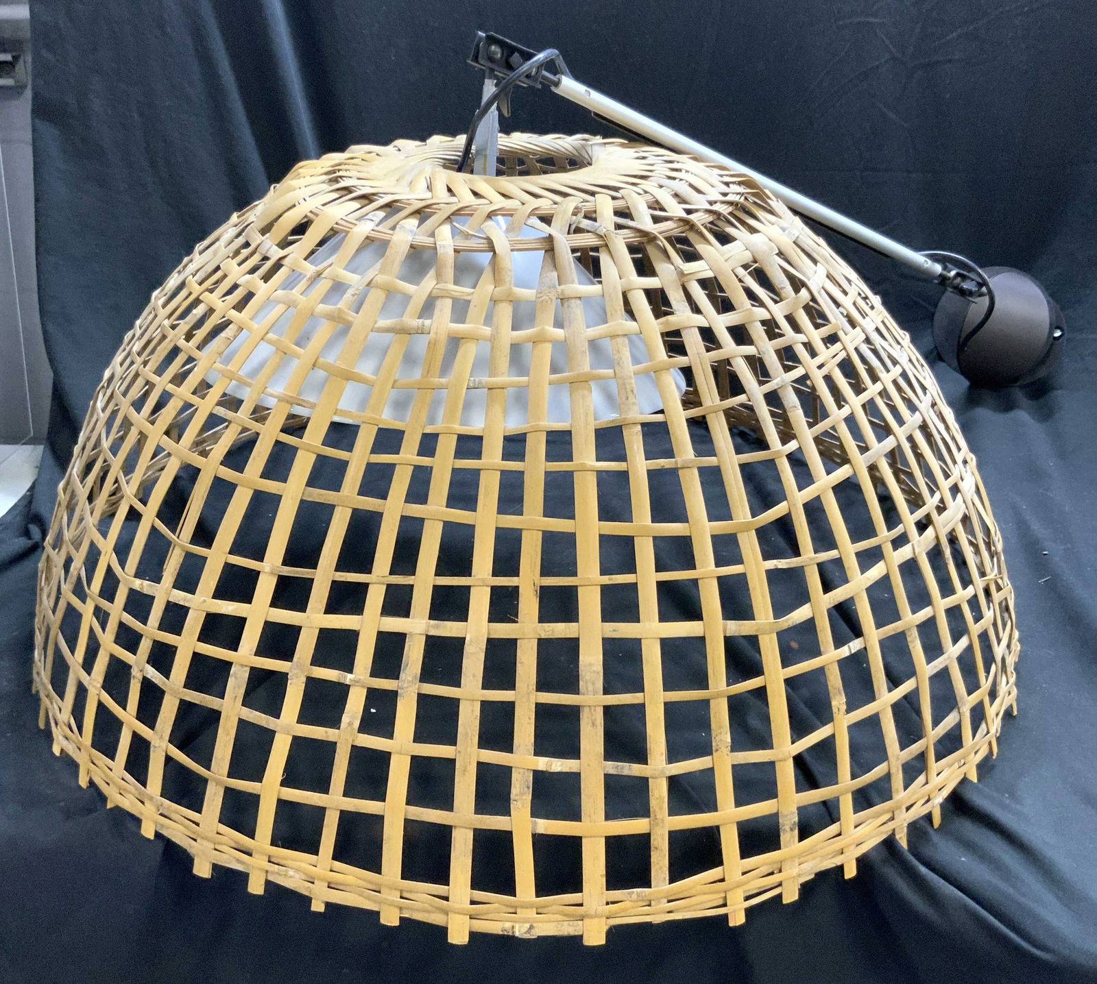 Woven Bamboo Dome Pendant Light: Pendant light has dome form. Piece appears to be bamboo. Interior has white toned plastic shade. Light has piece to attach to ceiling or wall Piece measures approximately 33 inches wide 18 inches tall