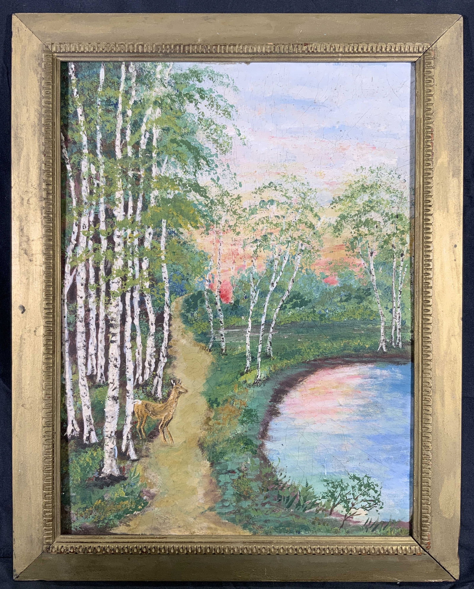 Framed Deer in a Birch Wood Acrylic Painting: Acrylic painting on board. Subject depicts a deer walking through a birch tree woods with a lake. Framed in a gilt wooden frame with a raised patterned inner window motif. Frame measures approx. 18.5 