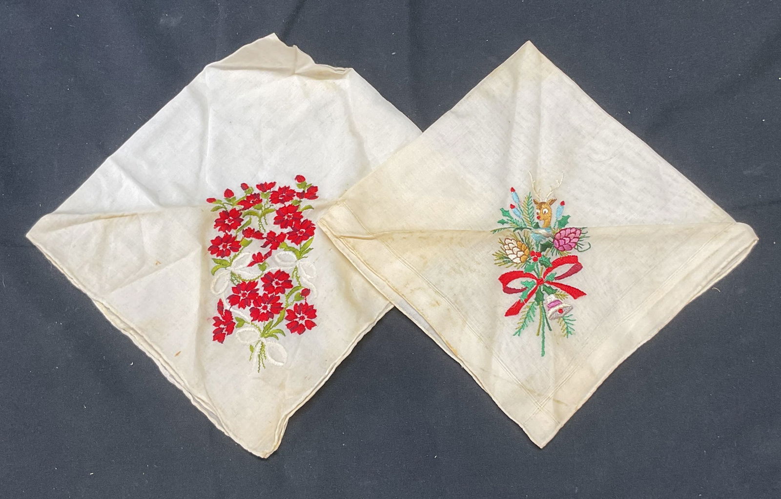 Lot 2 Vintage Floral & Holiday Handkerchiefs: Lot of 2 vintage white embroidered handkerchief with floral and holiday motifs. Materials feel like cotton. Larger piece measures approx. 14 x 13 inches. Both pieces have wear to material including bl