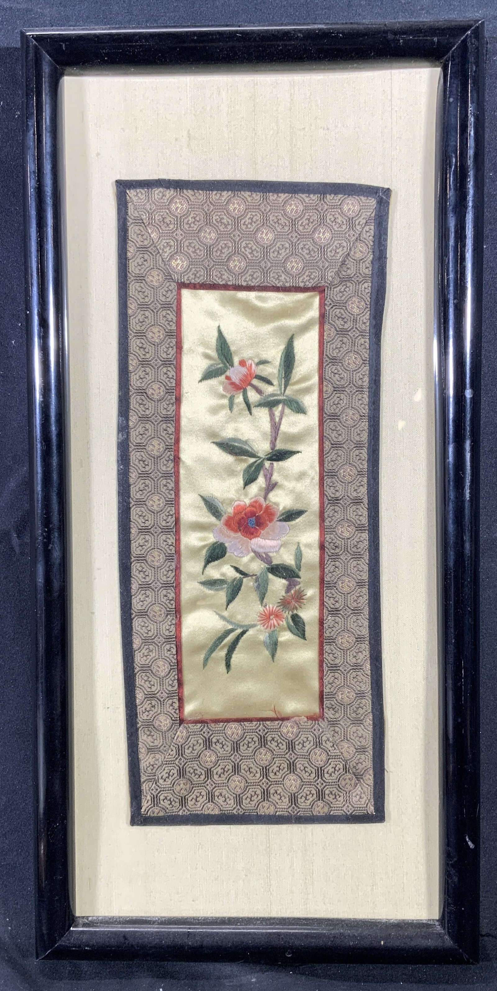 Framed Asian Style Hand Embroidered Silk Peonies: Hand embroidered silk. Subject depicts an Asian style peonies and foliage. Bordered with an Asian style pattern. Framed in a black wooden frame. Frame measures approx. 7.5 W x 15.5 H in. Window measur