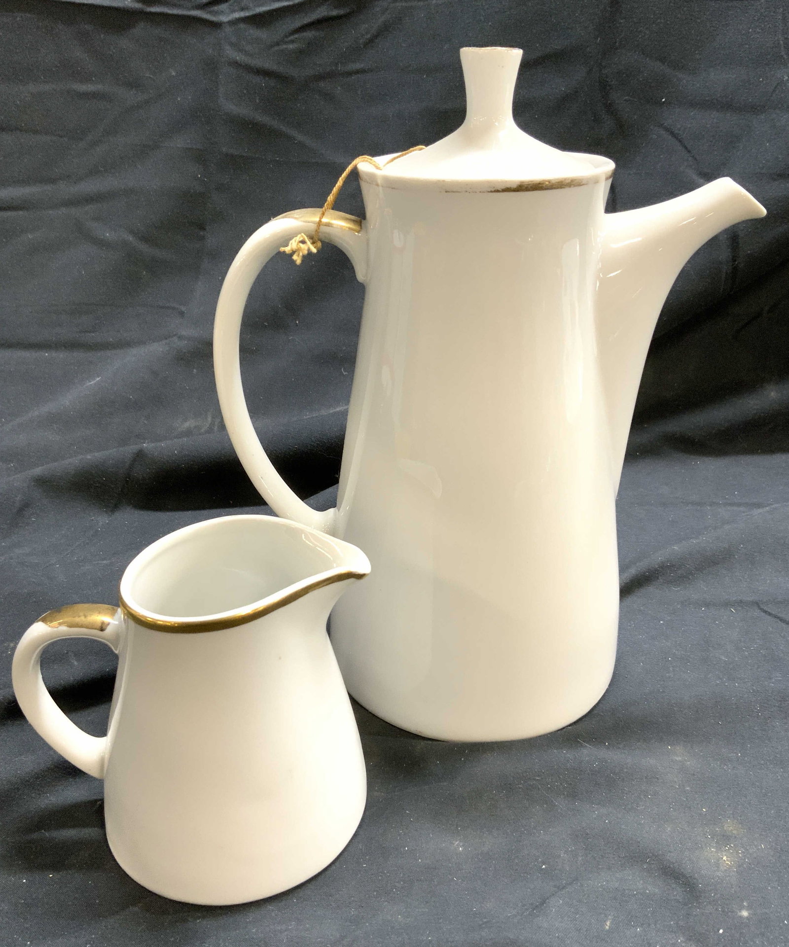 SHAFFORD CO GOLDEN HEIRLOOM Porc Cof Pot & Creamer: Tags on Undersides read SHAFFORD CO, Undersides are marked GOLDEN HEIRLOOM. Lot includes 1 coffee pot with lid & 1 creamer dish. Each piece is white toned and porcelain with gilt rims and gilt detail 