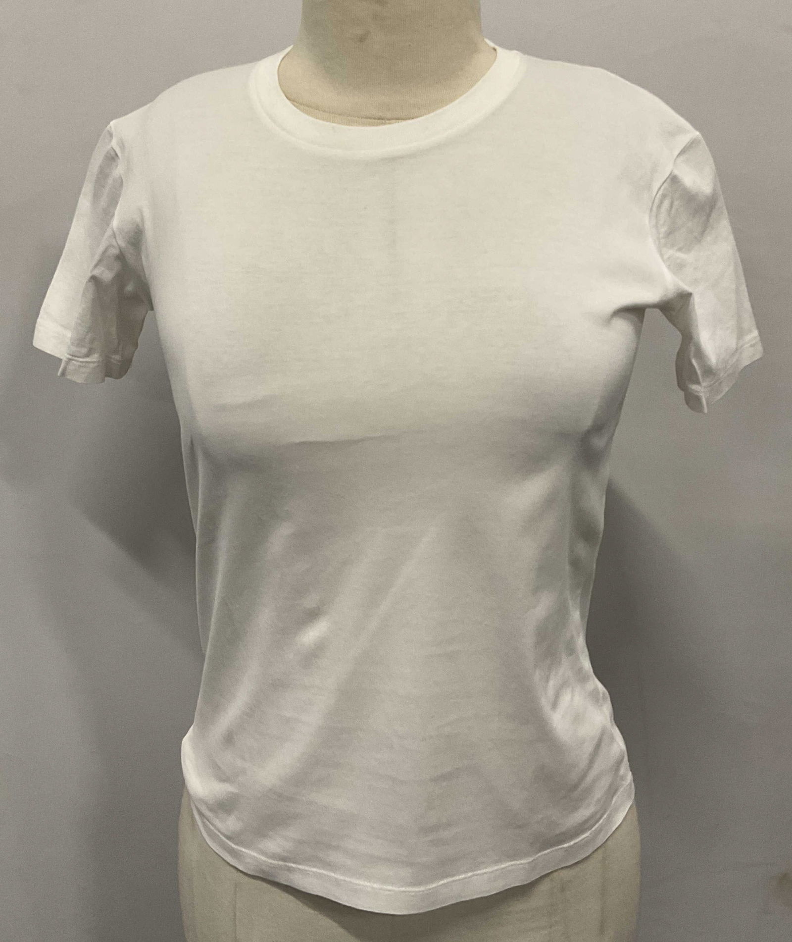 Prada Style White Short Sleeve Tee Shirt: Prada style white short sleeve crewneck tee shirt. Size XS. Material feels like cotton. Made in Romania. Some blemishes on neck. Prada label is hand sewn on garment. The Benefit Shop does not guarante