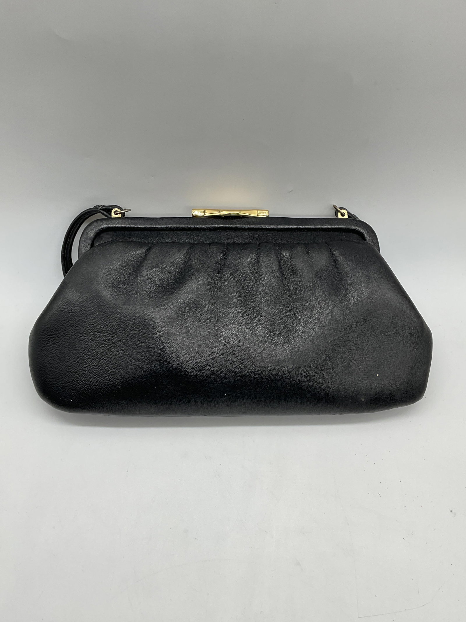 Vintage Black Leather Handbag: Vintage black leather handbag. Push clasp. Gold tone hardware. Zippered pocket on interior. Measures approx. 11.5 x 6 inches. Some wear to material including scratching and blemished observed. Ladies 