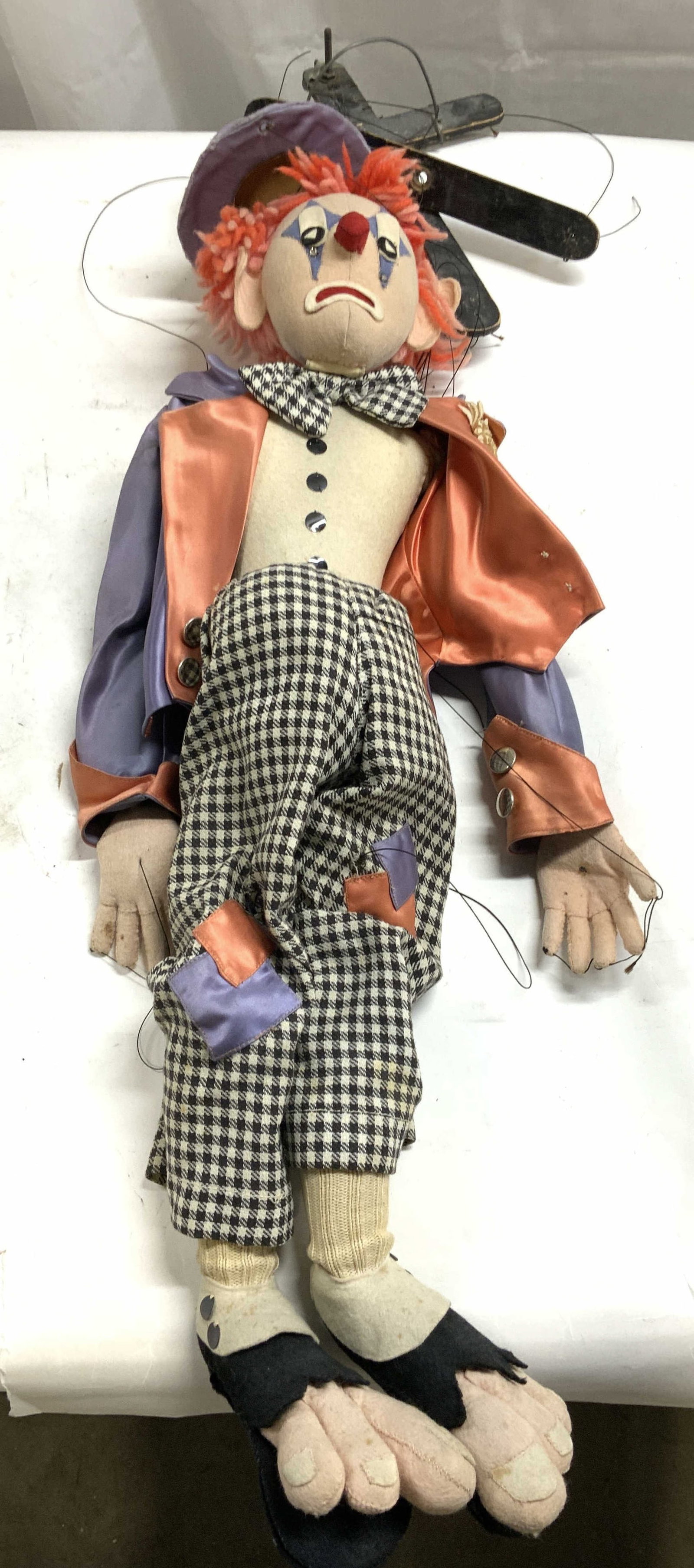 Vintage Felt & Yarn Clown W Hat Marionette: Marionette is vintage. Piece depicts a clown with hat, purple suit jacket, houndstooth patterned black and white toned pants, and toes bursting out of shoes. Marionette figure measures approximately 2