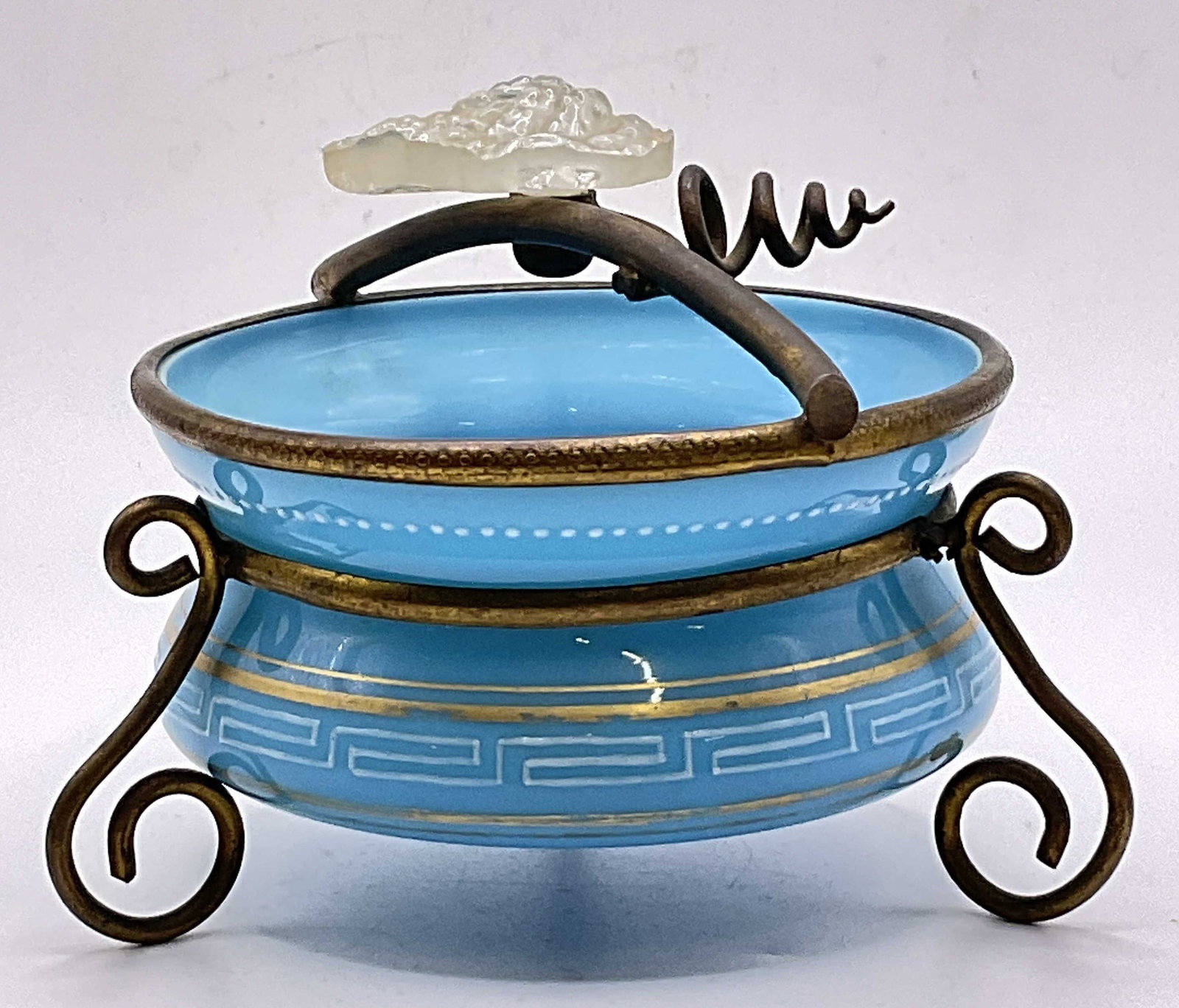 Vintage Blue Opaline Glass Bowl W/ Metal Stand: A vintage blue opaline glass bowl devoted with gilt and white paint. The bowl is wrapped in a metal stand with a colorless glass leaf accent. Scrolled feet to the stand. Measures approx. 3.5H x 3.75W