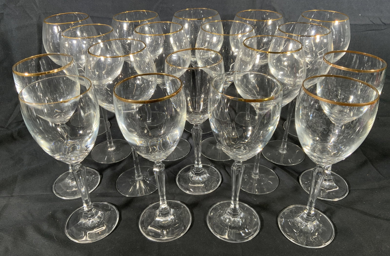 Lot 18 Gilt Rimmed Wine Glasses: Lot 18 wine glasses. Two kinds of wine glasses. One kind has a thin long stem and bulbous glass. Other is smaller and has a crystal cut stem and cup shaped glass. All have gilt on the glass rims. Wine