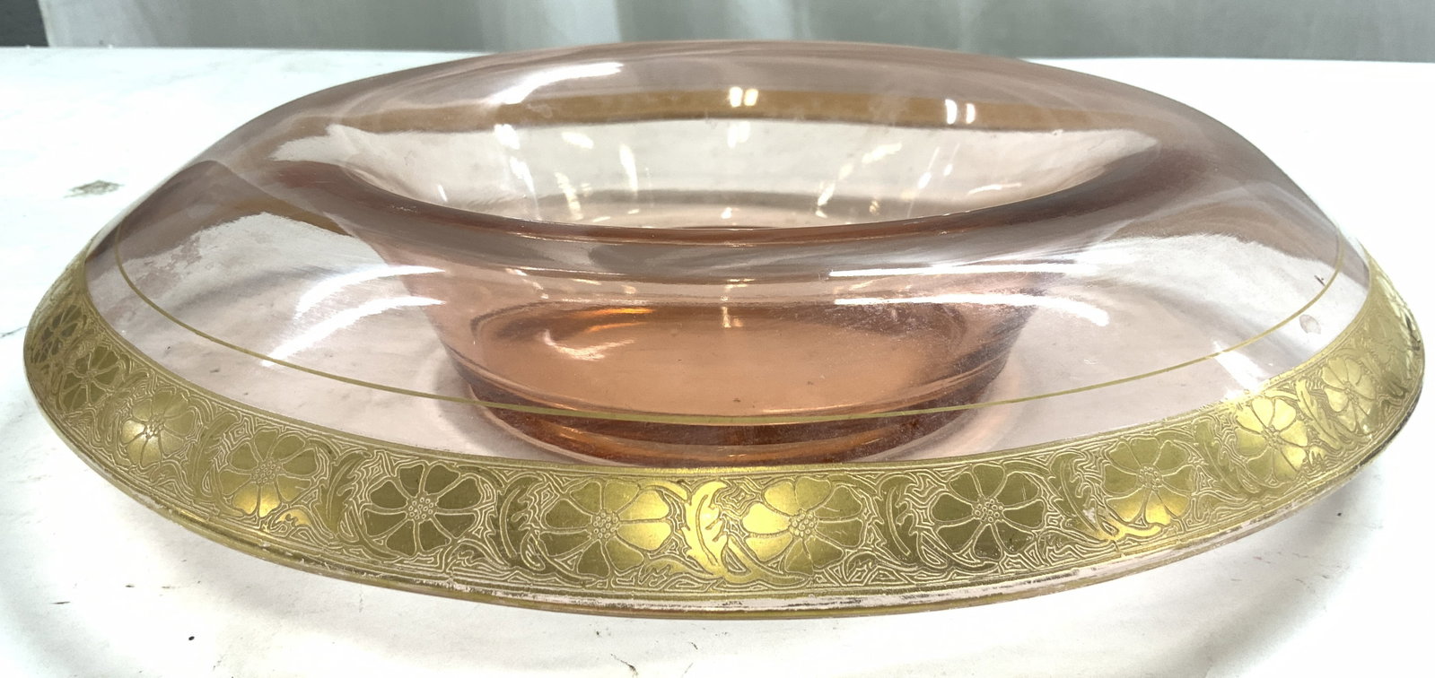 Vntg Pink Depression Glass Bowl W Gilt Trim: Glass dish is pink toned. Piece appears to be Vintage. Piece has gilt trim with ornate relief detail. Bowl has waterfall style sides. Piece measures approximately 13 inches wide and deep 3 inches tall