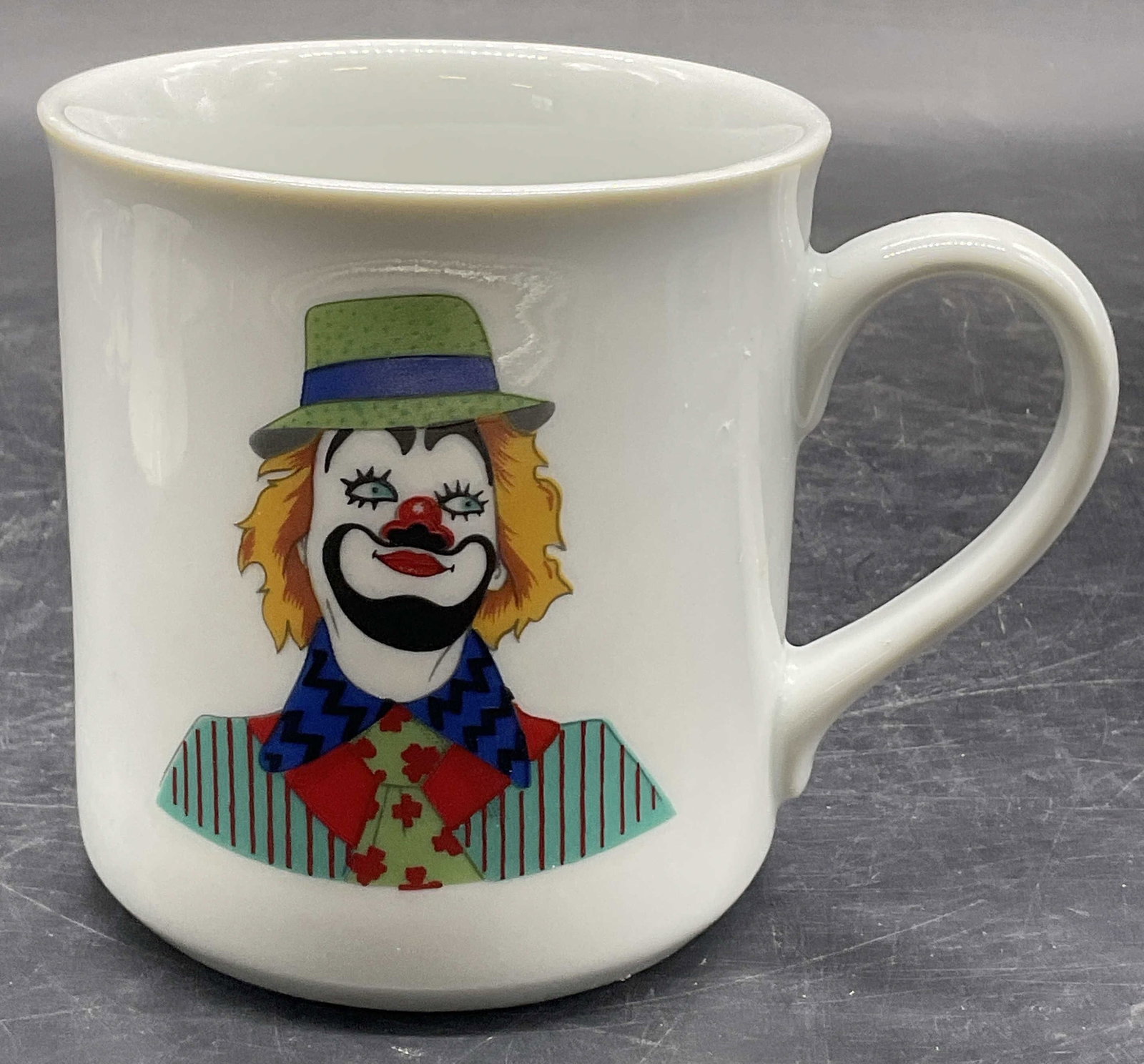 LEART Clown Motif Ceramic Mug, Brazil: LEART Clown Motif Ceramic Mug. Multicolored clown to obverse. Underside signed LEART, MADE IN BRAZIL. Measures approx. 3.5H x 4.25W in. Width includes handle. Wear consistent with age, use, and exposu