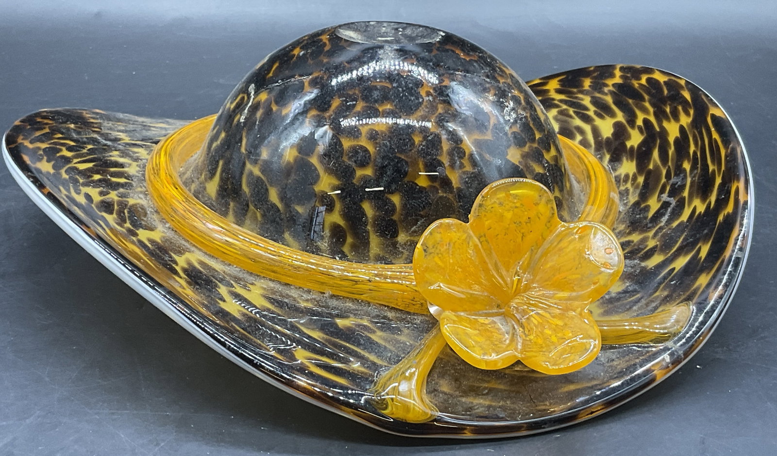 Art Glass Leopard Pattern Floral Ribbon Hat: Art Glass Leopard Pattern Floral Ribbon Hat. Pulled glass orange flower ribbon wrapped around the hat. Pontil to the top of the hat. Underside of hat is a white hue. Measures approx. 2H x 9.5W in. Res
