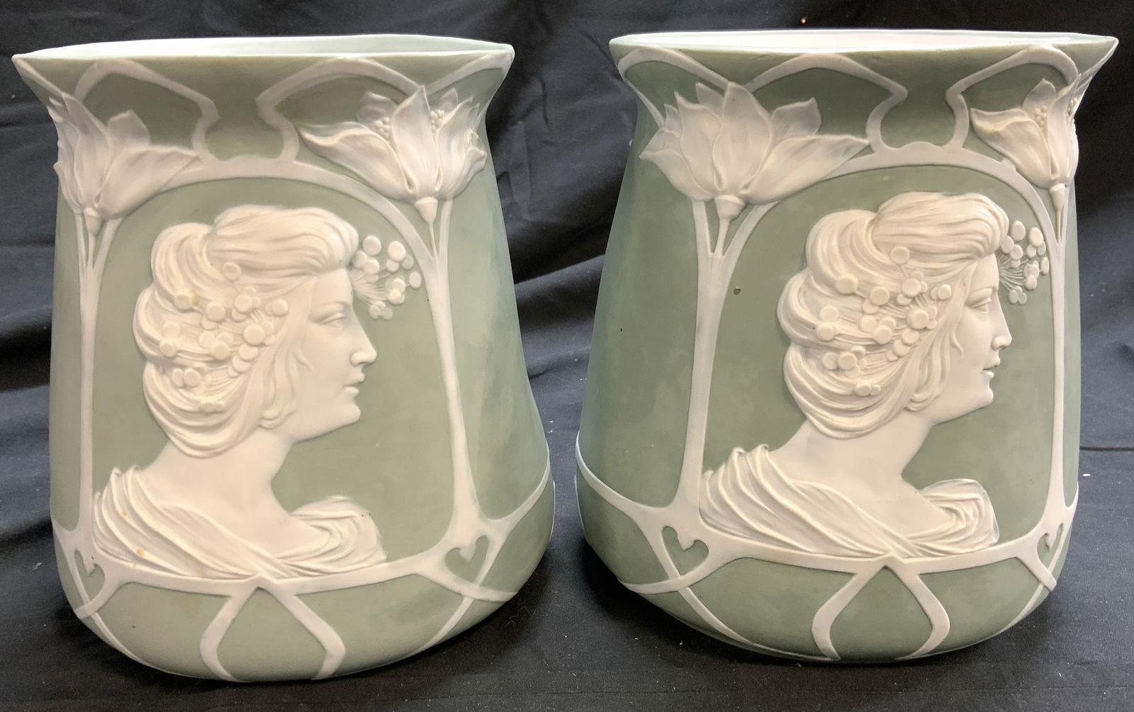 Pair Art Nouveau Jasperware Vessels Green: Lot includes 2 vessels. Each are light green with white toned floral, leaf & female figure detail. Vessels each have rims which lean outwards. One piece has white toned interior. Vessels each measure