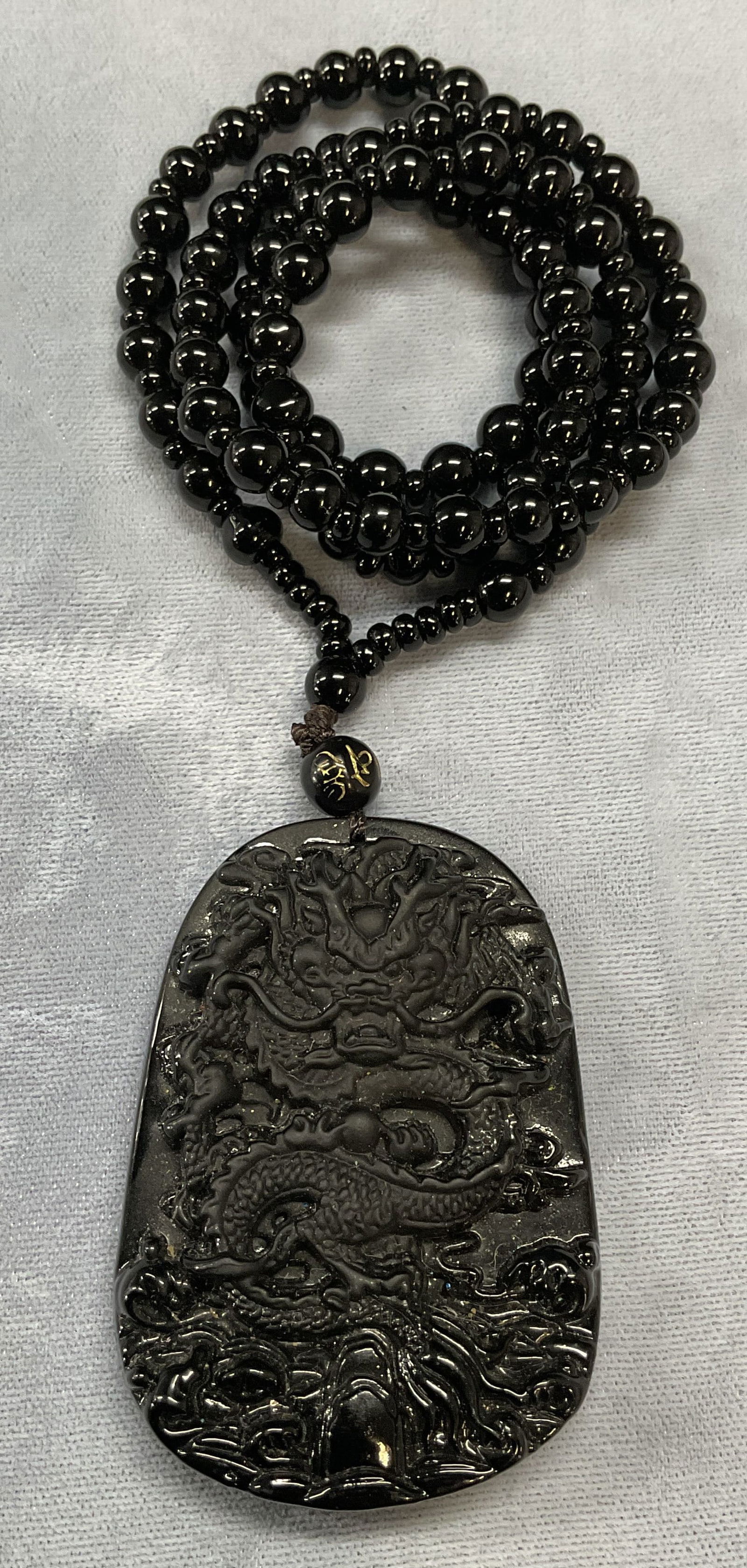 Asian Black Dragon Pendant Necklace: Asian black beaded pendant necklace with dragon motif pendant. Appears to be obsidian. Drop length approx. 11.5 inches. Pendant measures approx. 2.5 x 1.5 inches. Some surface wear including scratchin