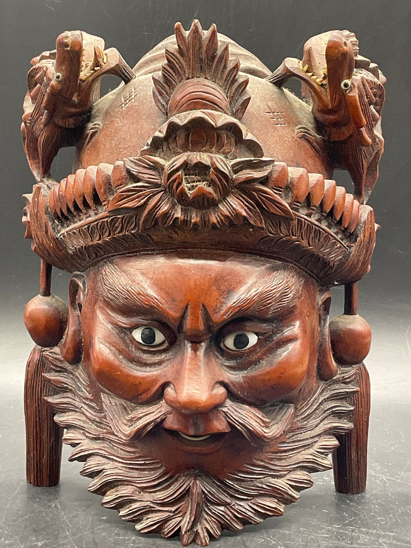 Vintage Asian Figural Carved Wood Mask Wall Decor: A vintage Asian figural carved wood mask. White accents to the teeth and eyes. The white accents are possibly bone or resinous material. The figural mask has dragons to the top. Piece has some weight