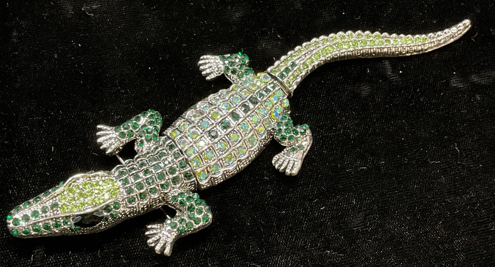 Articulated Silver Tone Crystal Alligator Brooch: Articulated silver tone alligator motif brooch/pendant with green crystal decoration. Hinge pin and bail on underside. Measures approx. 5.5 x 1.75 inches. Some surface wear including scratching observ