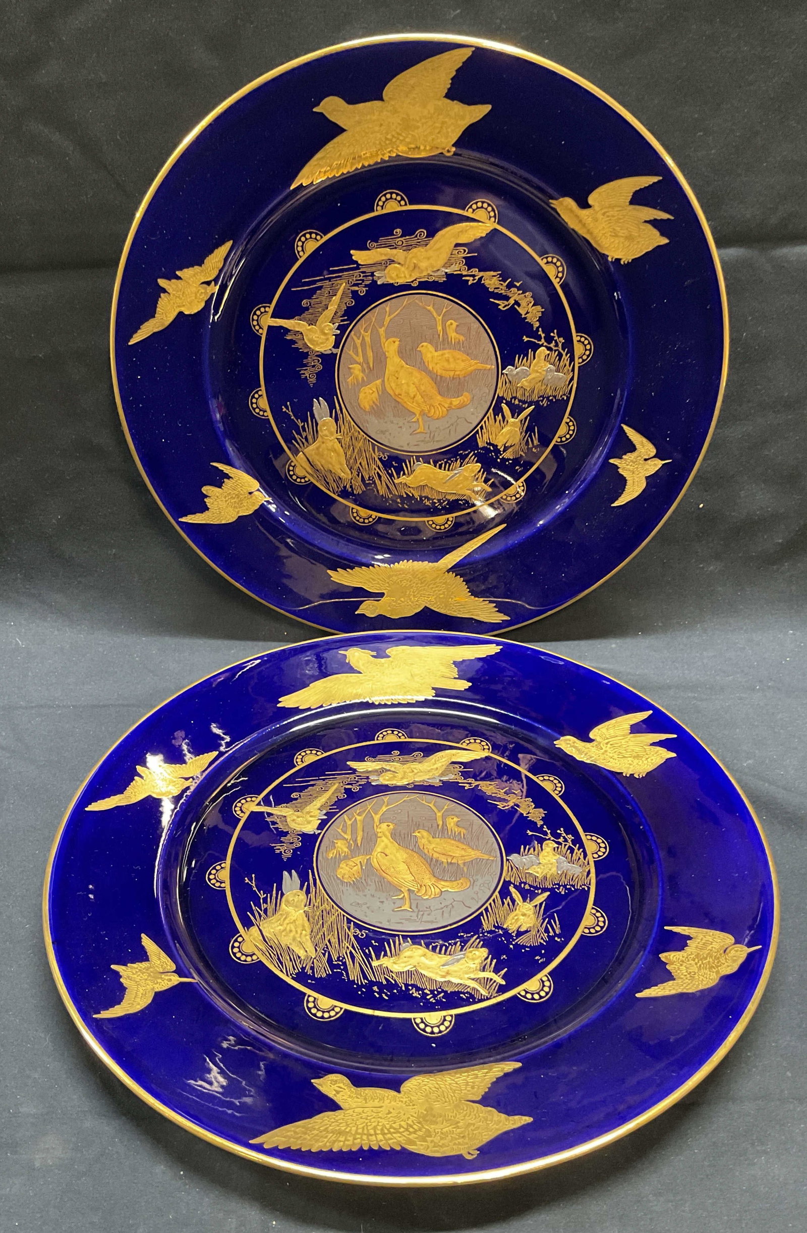 Pair Antique Gilt Cobalt Porcelain Cabinet Plates: Pair of antique Aesthetic Movement style porcelain cabinet plates with hunting bird and animal motifs. Cobalt blue ground with gilt and silvered decoration. Numbered by hand on undersides, H 2393. Mea