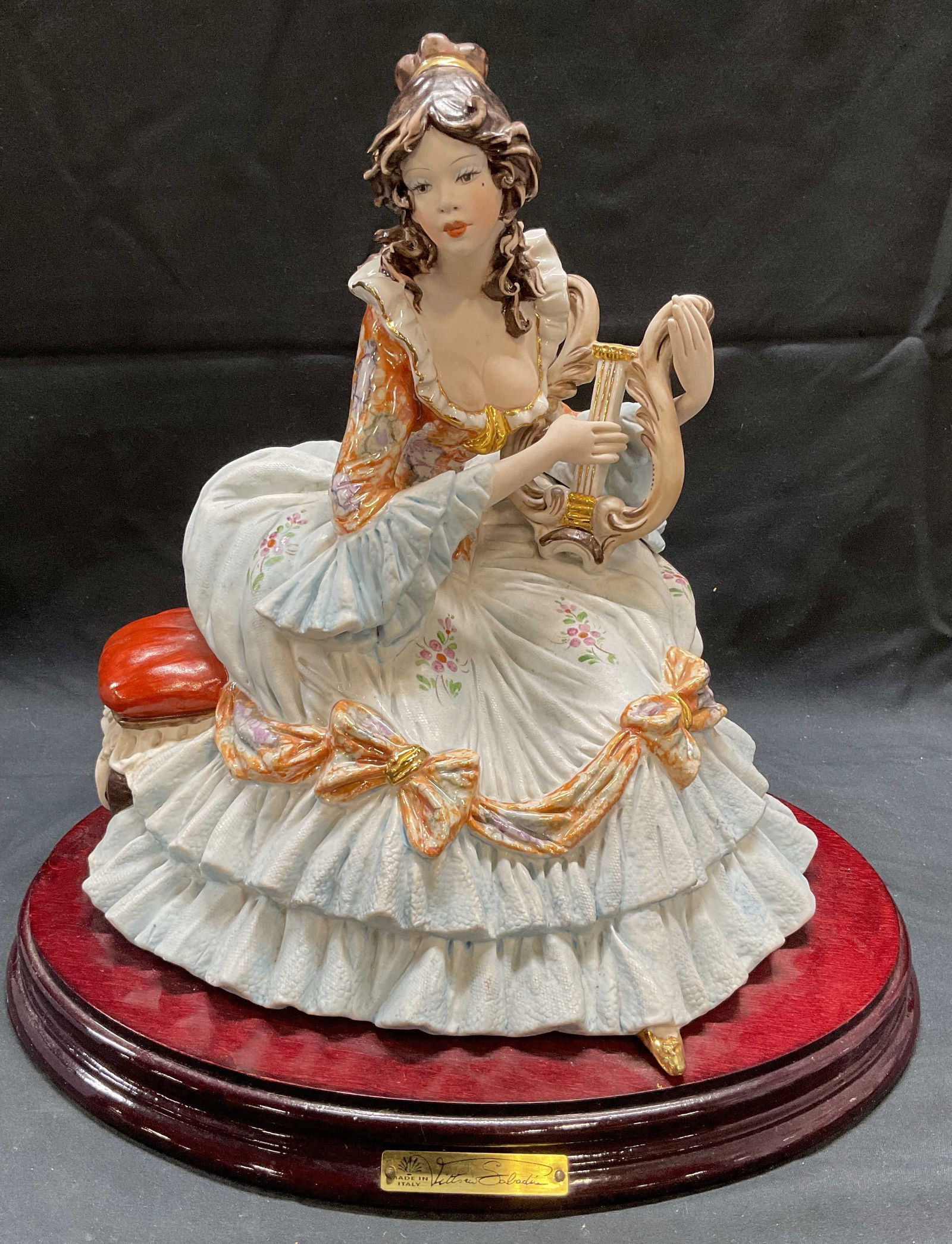 Vittorio Sabadin Porcelain Woman Playing Lyre, IT: Capodimonte porcelain figural of a woman playing the lyre by Vittorio Sabadin. Hand painted. Signed on reverse and plaque. Porcelain figurine on wood base. Made in Italy. Measures approx. 11.5 x 8 x 1