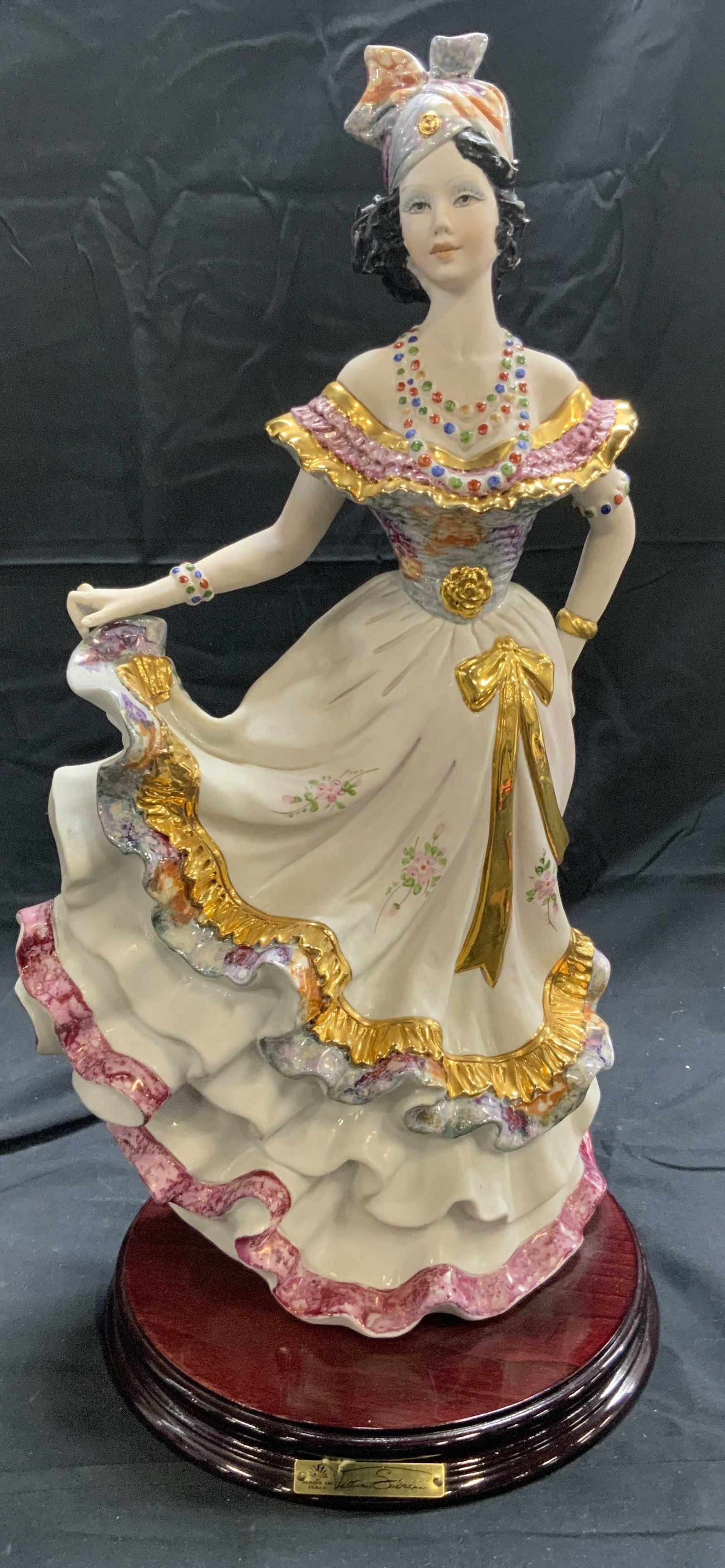 VITTORIO SABADIN Gypsy Lady Porc Figure ITALY: Plaque reads VITTORIO SABADIN MADE IN ITALY. Piece is porcelain. Depicts a female gypsy dancer. Piece has multi toned floral, leaf and gilt detail. Figure has mahogany toned circular form base. Piece 