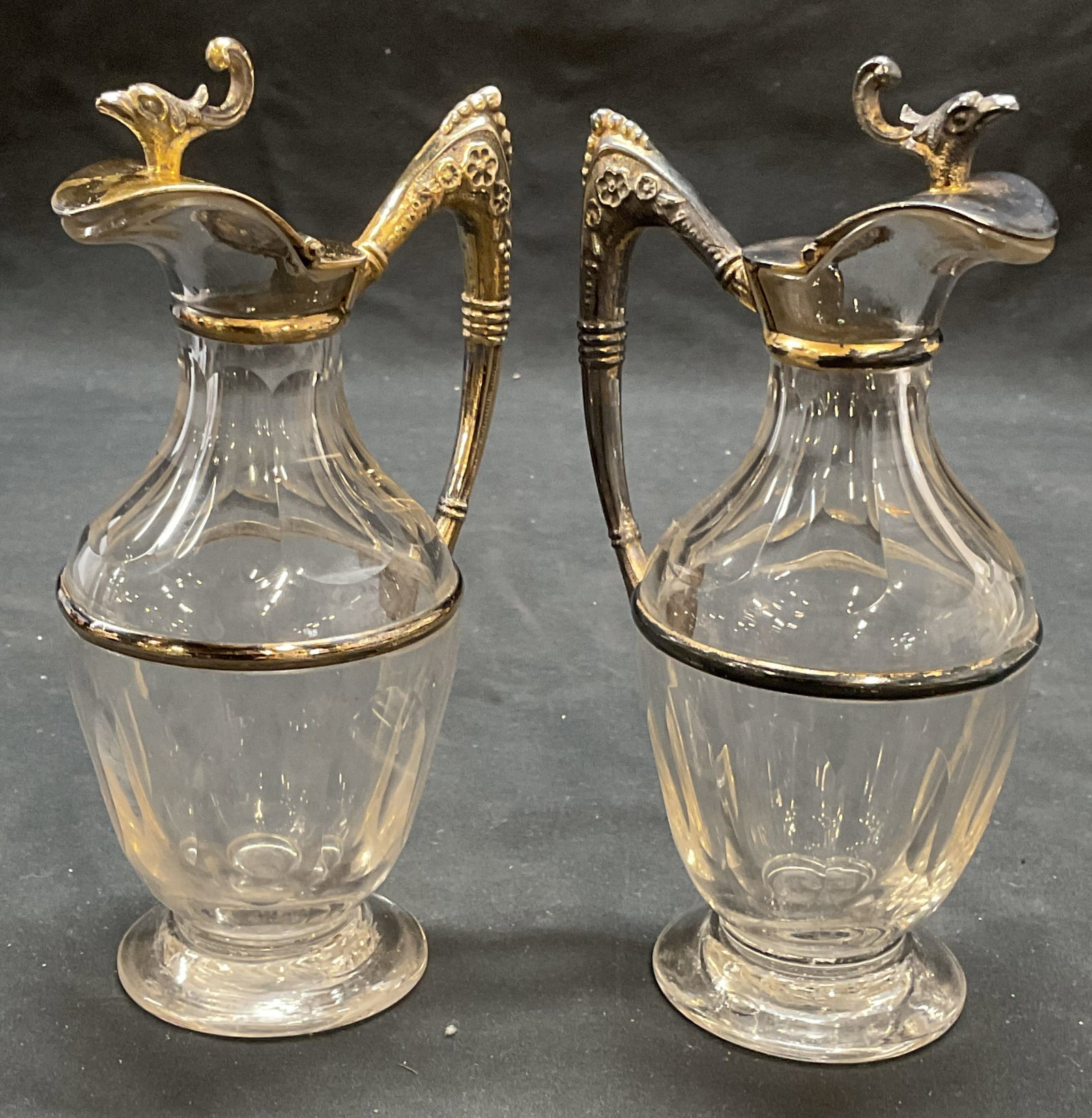 Pair Vtg Glass & Gilt Silver Tn Condiment Cruets: Pair of vintage hand blown faceted glass cruets with gilt silver tone handles and lids. Raised floral and bird design on metal. Measure approx. 6 x 2.5 inches each. Both pieces have surface wear inclu