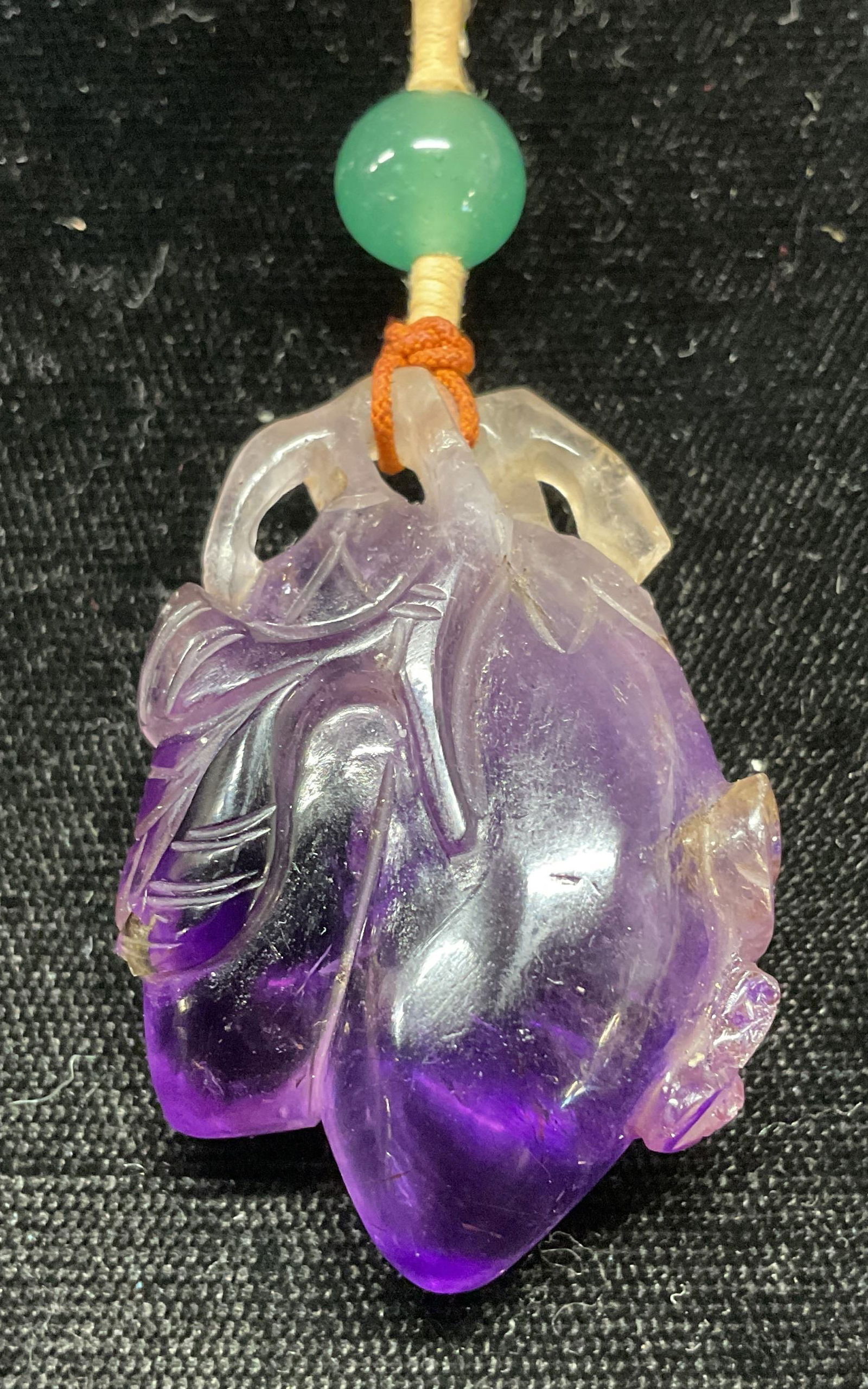 Vintage Amethyst Eggplant Pendant Necklace: Vintage carved amethyst gemstone eggplant motif pendant with jade glass bead on purple cord. Drop length approx. 13.5 inches. Pendant measures approx. 1.75 x 1 inches. Some surface wear including scra