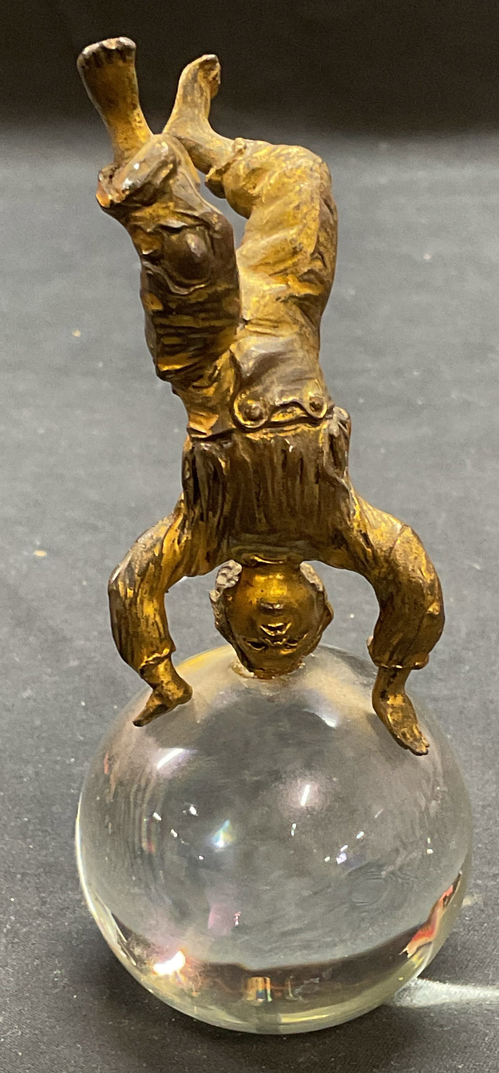 Gilt Child Handstand Figural on Crystal: Gilt metal child figural in handstand pose on crystal orb. Measures approx. 2 x 4.75 inches. Some surface wear including scratching observed. Child figural, gilt figural, crystal figural, decorative a