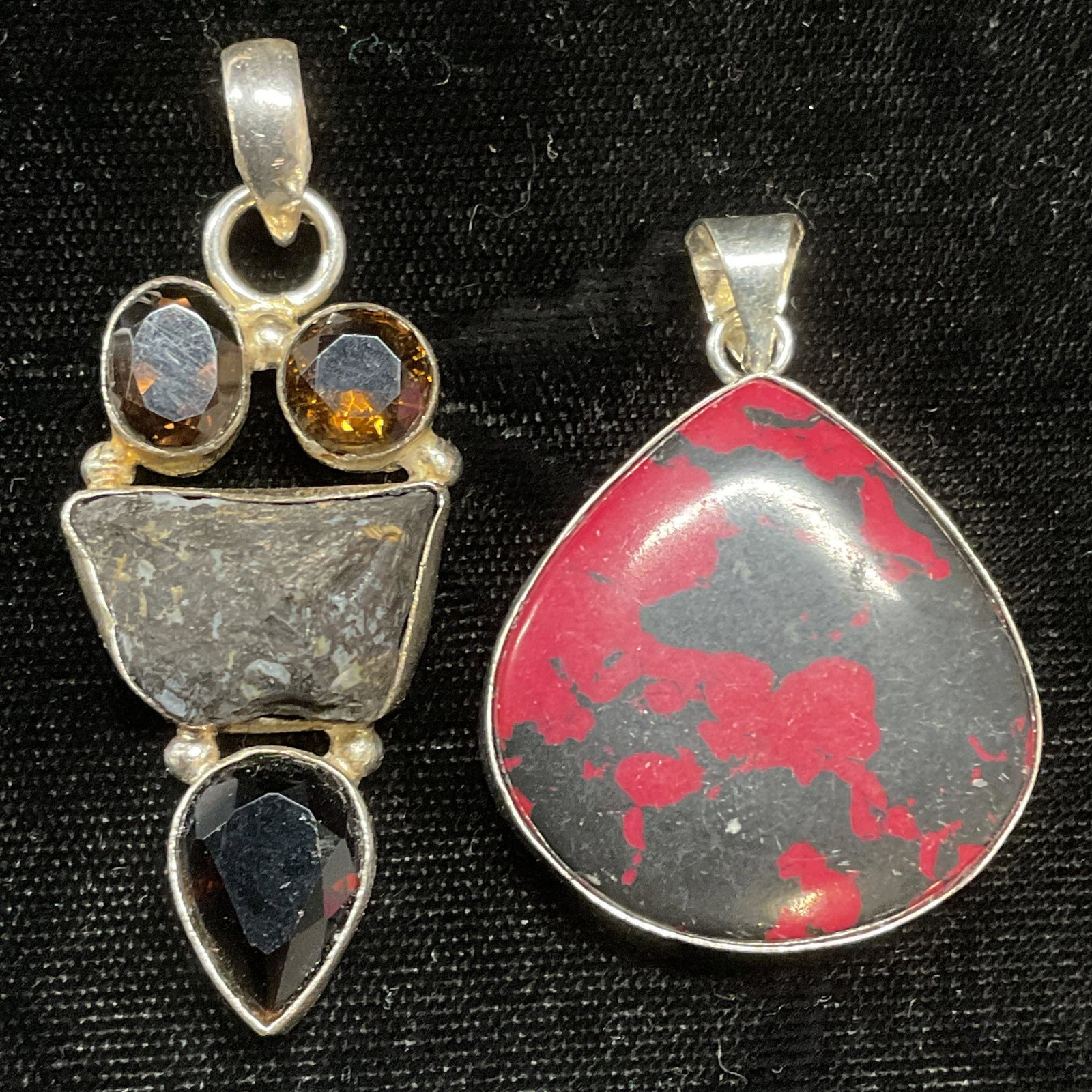 Lot 2 Sterling Silver Stone & Crystal Pendants: Lot of 2 sterling silver semiprecious and crystal pedants. One piece with drop shaped red and black stone. Measures approx. 1.25 x 1.25 inches. One piece with amber toned crystals and grey stone. Meas