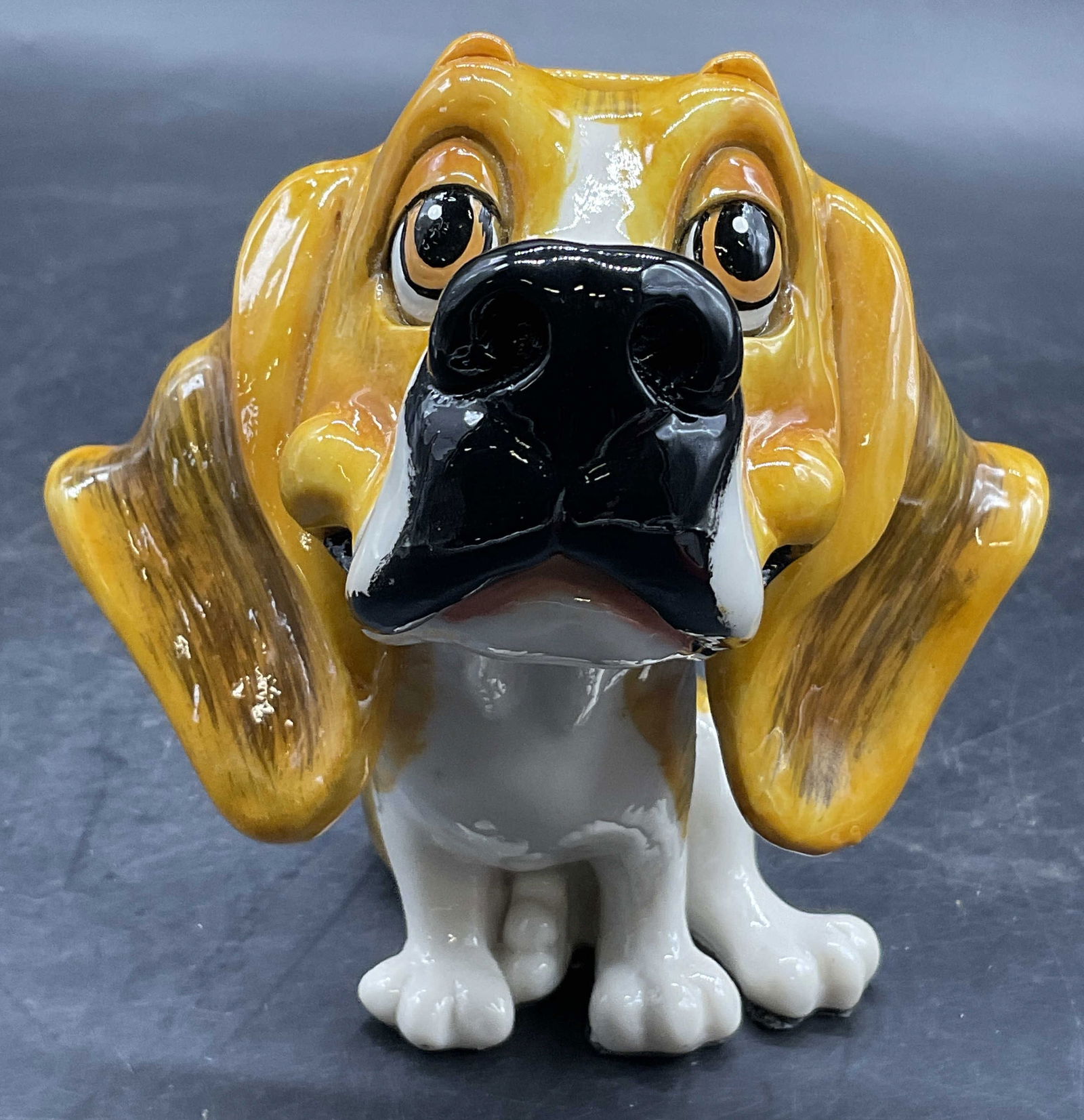 08 CH ARORA Signed Dog Figural Eyeglass Stand: Resinous dog form eyeglass stand / display. Divot to the top of the dogs head for resting glasses. Signed 08 CH ARORA to one side. Black fabric affixed to underside. Measures approx. 4.5H x 5W in. Sur