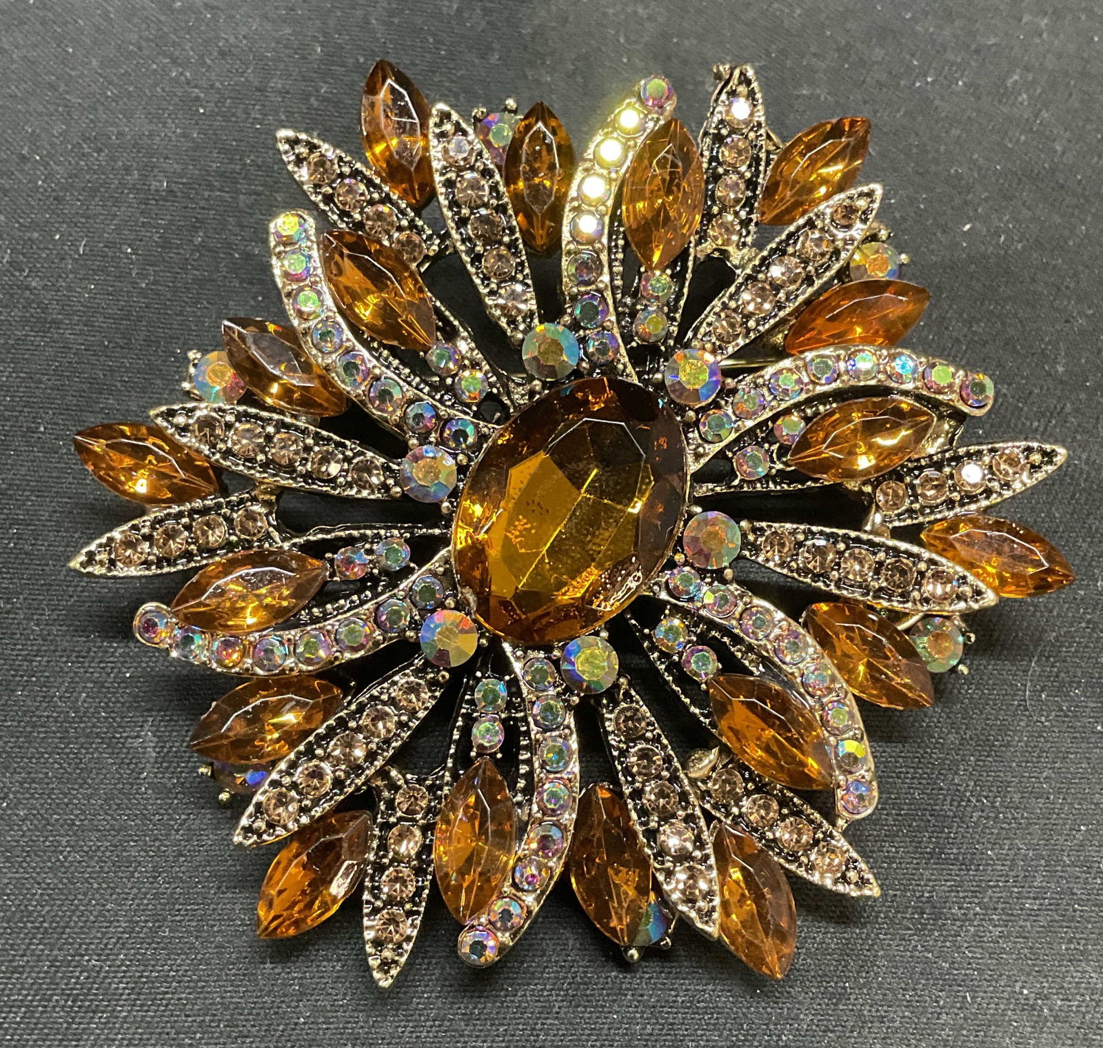 Gold Tone Crystal Flower Brooch: Gold tone flower motif brooch with amber toned crystal. Hinge pin on underside. Measures approx. 2.5 inches wide. Some surface wear including scratching observed. Estate jewelry, costume jewelry, cock