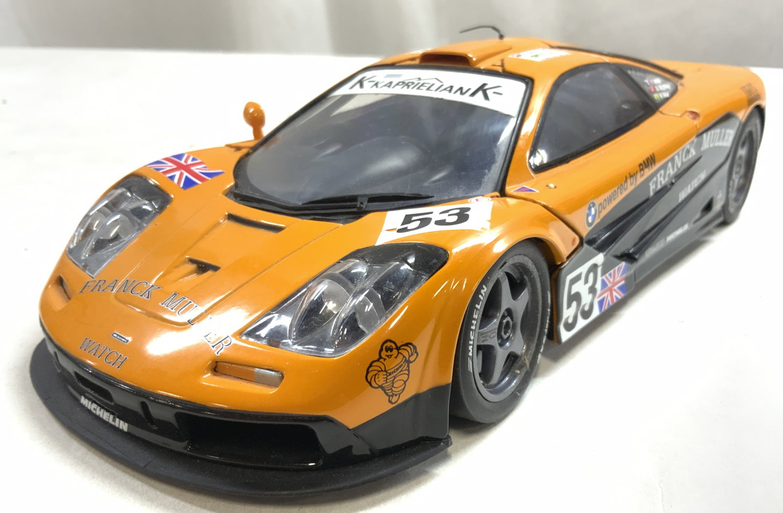 UT MODELS Die Cast MCLAREN F1 Car: Underside is trademarked UT MODELS. Underside also reads 1/18 MCLAREN F1. Piece has articulated Dihedral doors. Piece is orange and black toned with no 53, the Union Jack flag, & trademarks such as FR