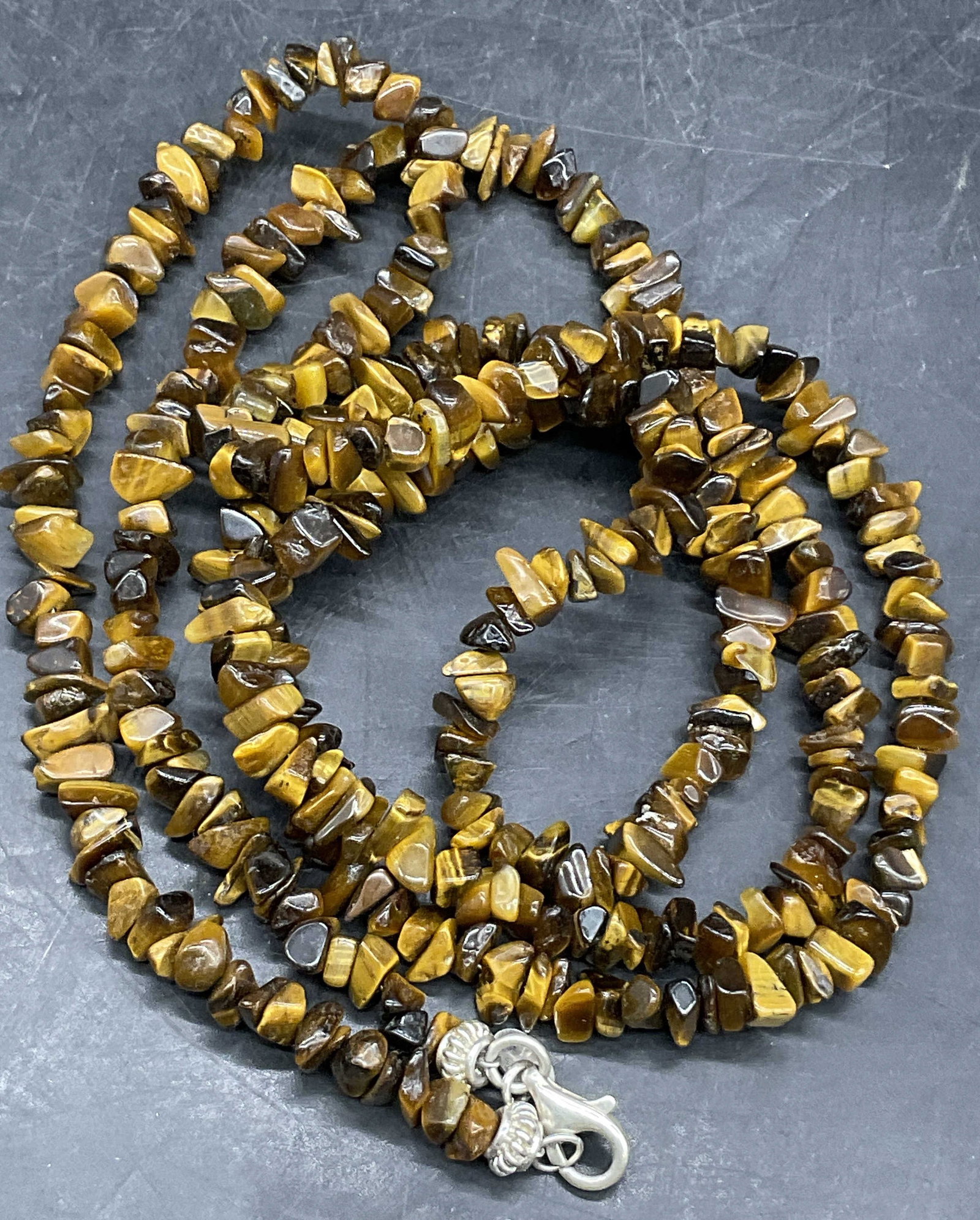 925 Sterling Silver Tigers Eye Shard Necklace: 925 Sterling Silver Tigers Eye Shard Necklace. Lobster claw clasp closure marked 925. Charm adjacent to clasp marked SX925. Total weight 2.02 in. Necklace length measured end to end approx. 40 inches.