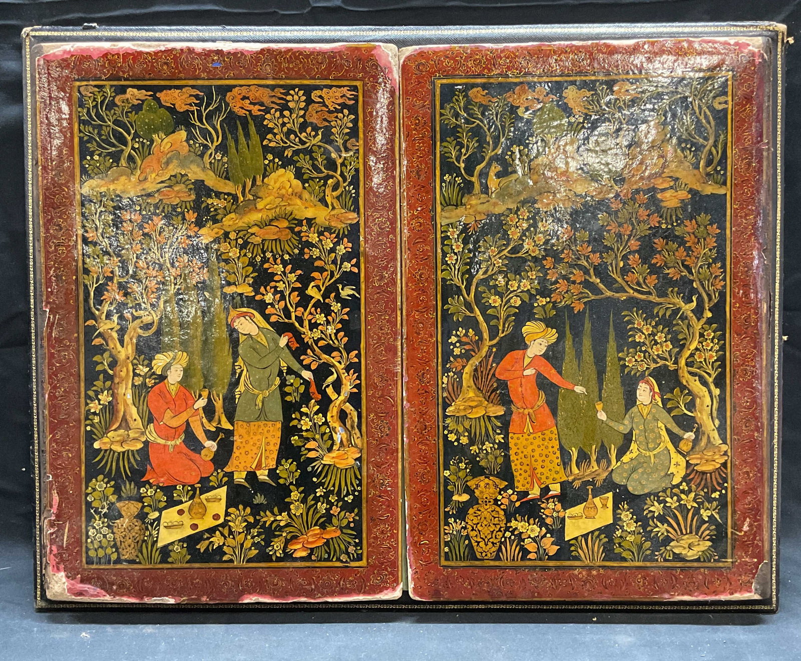Persian Figural Painting on Album: Mounted album with Persian painting on cover. Hand painted over paper and varnished. Depicts couple with landscape background. Mounted on black covered backing with gilt detail. Measures approx. 16 x 