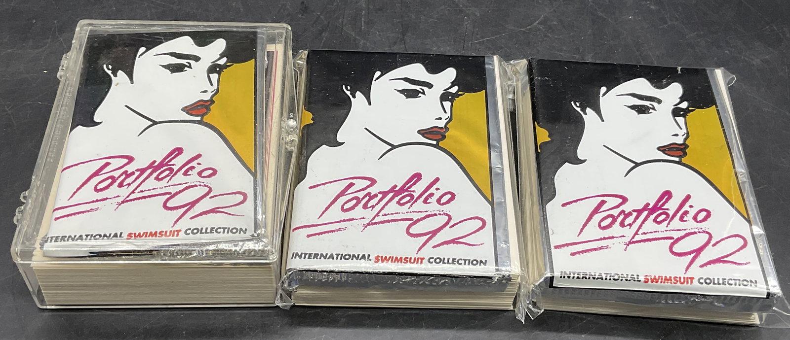 Grp Lot PORTFOLIO 92 Swimsuit Trading Cards: Group lot PORTFOLIO 92 Swimsuit Trading Cards. Some cards are contained in a hard plastic case, not all cards have been examined. Two packages are sealed with plastic packaging and tape, unexamined. S