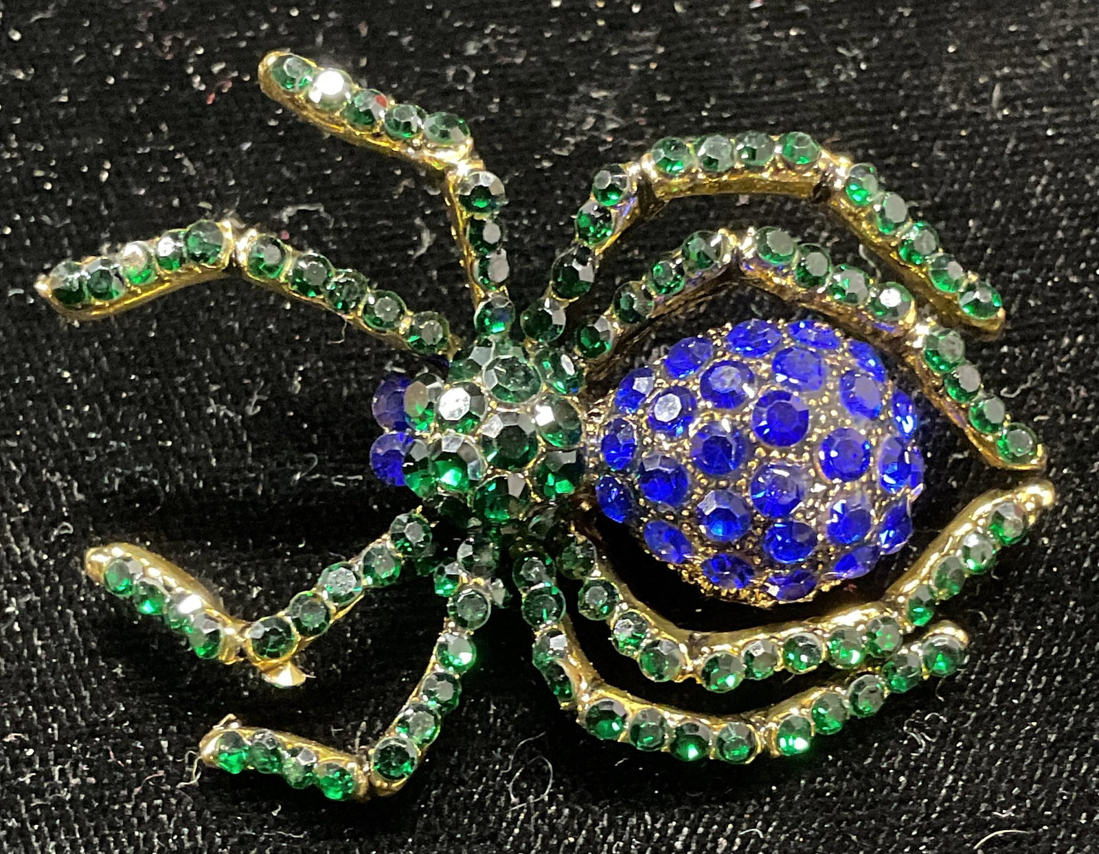 Gold Tn Green & Blue Crystal Spider Brooch: Gold tone spider motif brooch with green and blue crystal decoration. Hinge pin on underside. Measures approx. 2 x 1.5 inches. Some surface wear including scratching observed. Jewelry, estate jewelry,