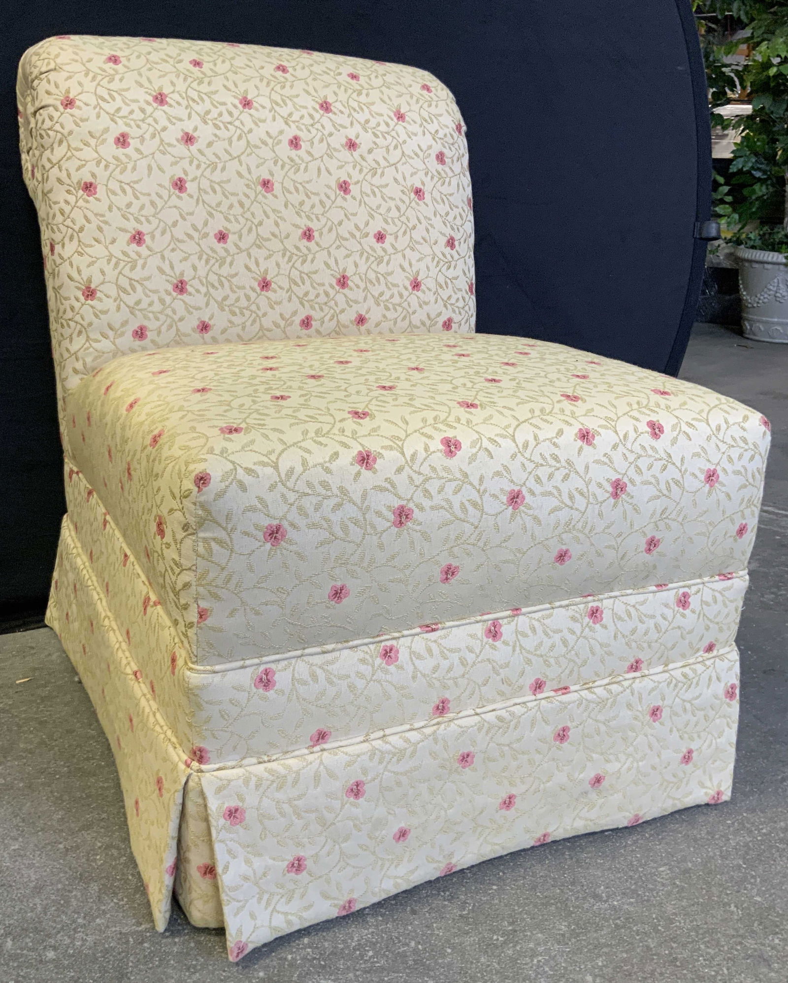 Vintage Floral Armless Skirted Chair: Chair is vintage. Piece has tan toned upholstery with floral, vine & leaf pattern detail. Chair is armless and skirted. Foot of chairs are Upholstered in match in fabric. Piece measures approximately
