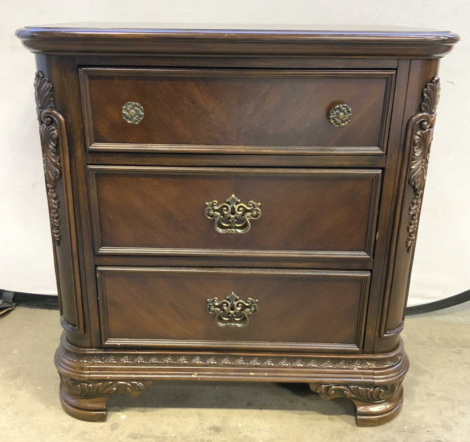 MERIDIAN INTL 3 Drawer Wooden Nightstand: Tag on backside reads MERIDIAN INTERNATIONAL. Nightstand is brown toned appears to be wooden possibly veneer. Piece has 3 drawers. Top drawer has 2 gilt metal knob style handles. Lower 3 drawers have 