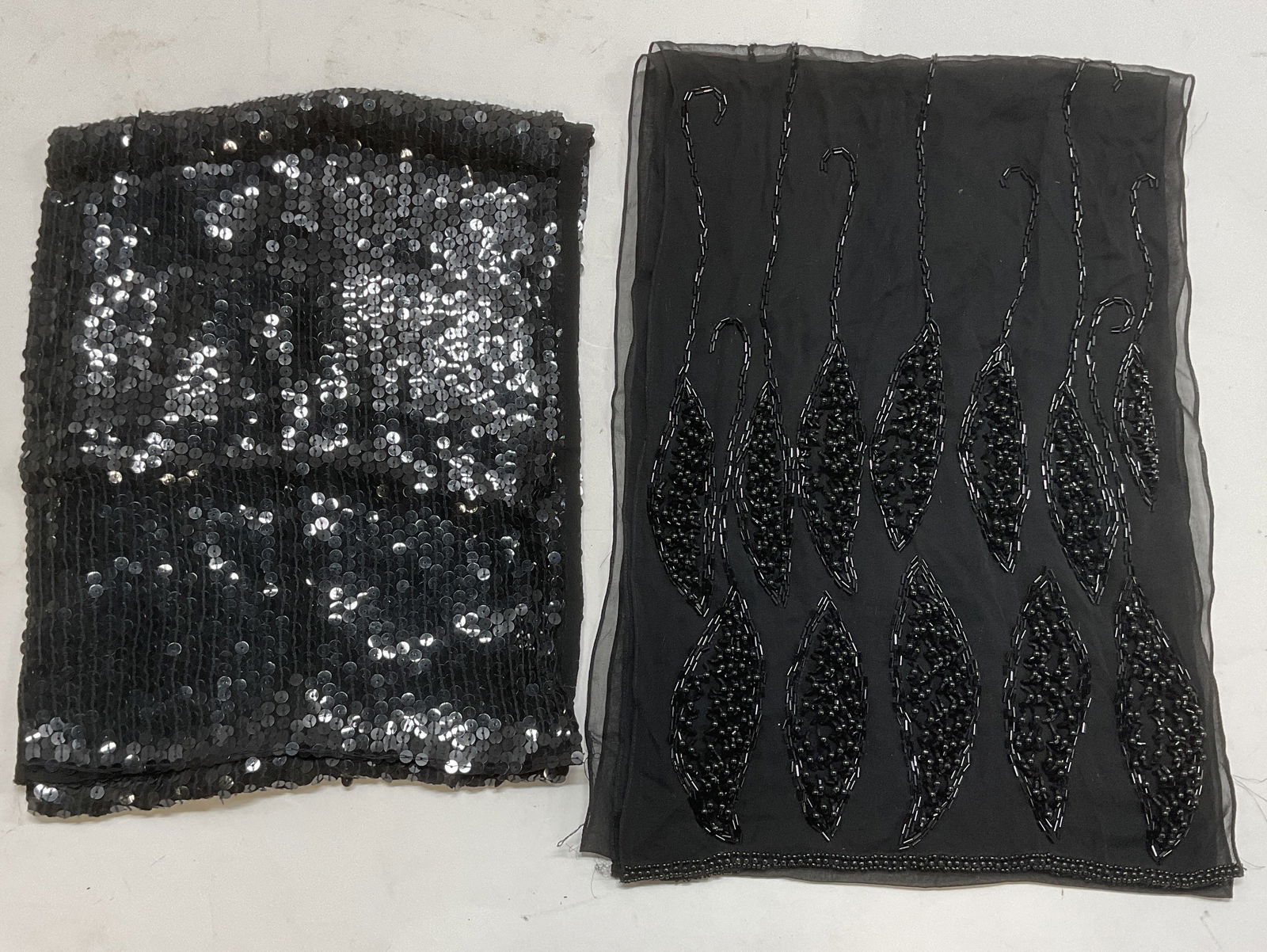 Lot 2 Black Beaded & Sequin Scarves: Lot of 2 black scarves with beaded and sequin designs. Synthetic materials. Longer scarf measures approx. 68 inches long. both pieces have some wear to materials consistent with exposure. Ladies scarf