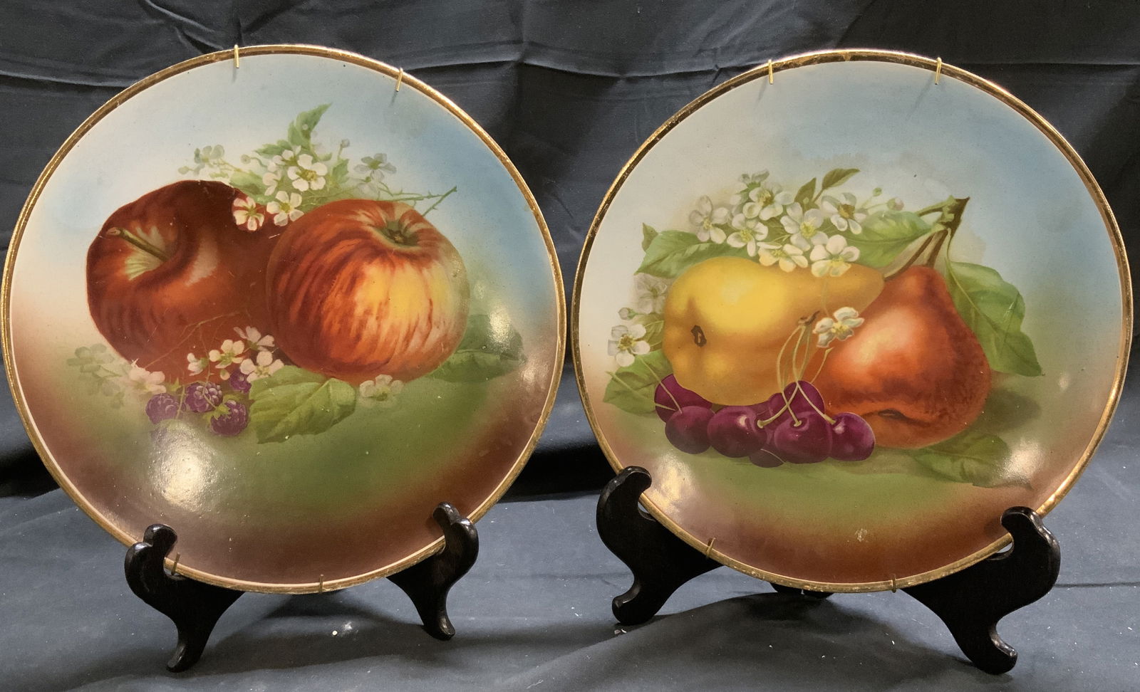 Lot 2 Porc Plates W Fruit Detail & Gilt Rims: Lot includes 2 plates. Each are porcelain. Plates each have floral, leaf, & fruit detail. Each plate has gilt rims. Plates each measure approximately 9.5 inches diameter. Plates, porcelain plates, fru