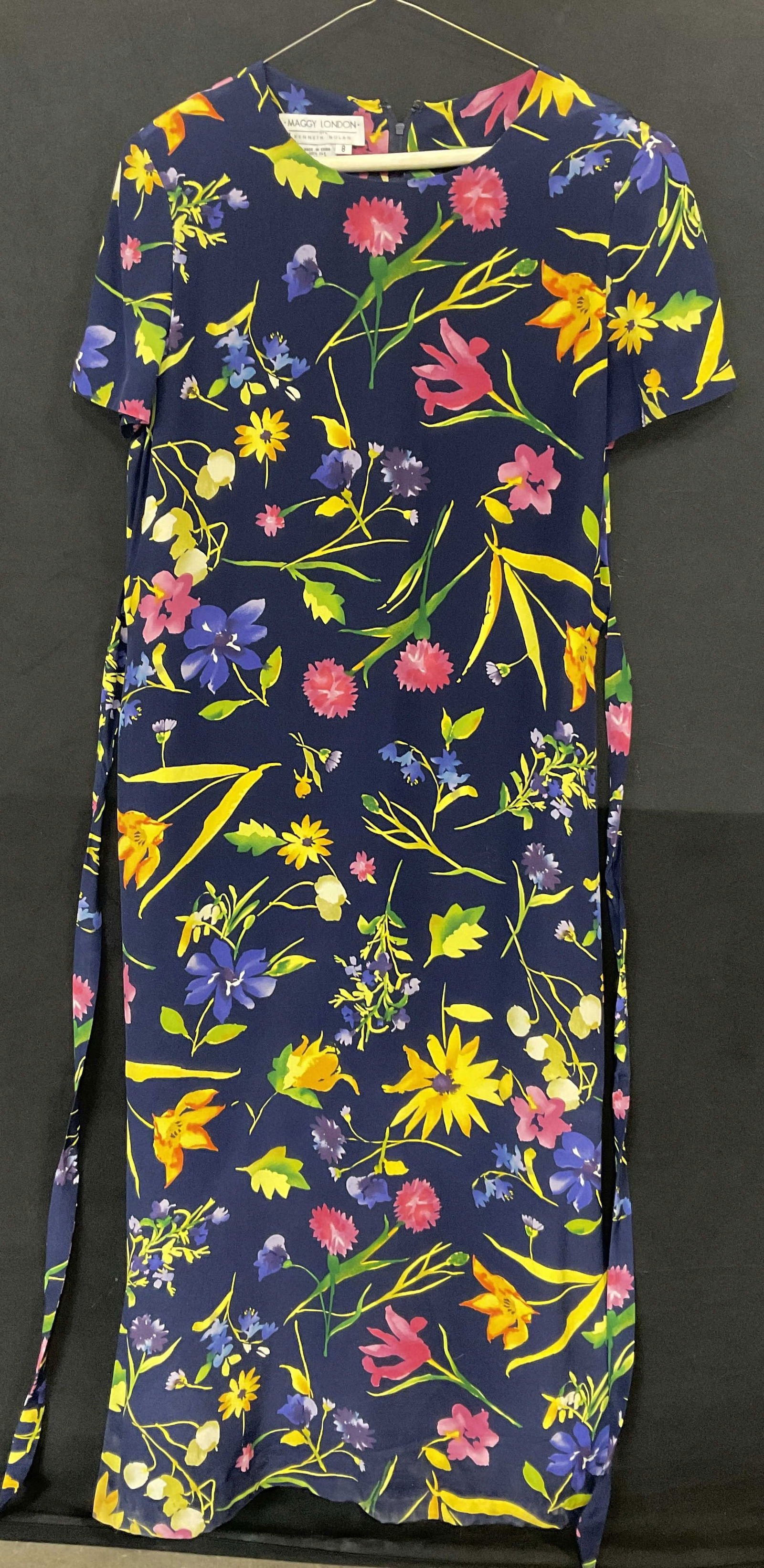 MAGGY LONDON by KENNETH NOLAN Floral Dress: MAGGY LONDON by KENNETH NOLAN Floral Patterned Dress. Deep navy blue hued short sleeve dress featuring multicolored florals throughout. Attached fabric belt towards waist. Tag reads MAGGY LONDON by KE