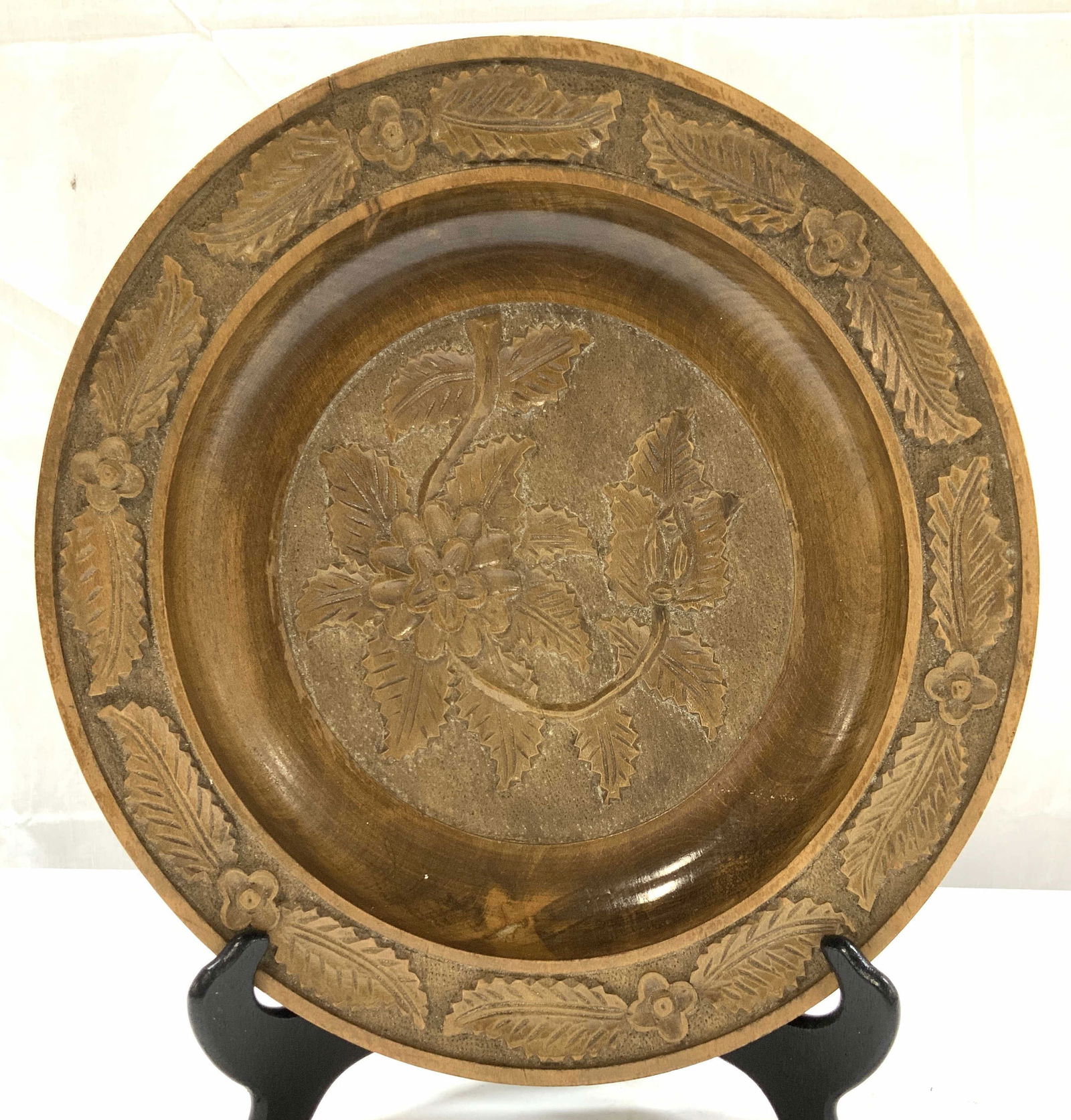 Carved Wooden Centerpiece Plate: Hand carved vintage wooden plate with raise leaf and flower pattern. Lightweight wood. Measures approx 13 in. Diameter. Has a crack on rim and appears a bit warped or may be part of the handmade trade