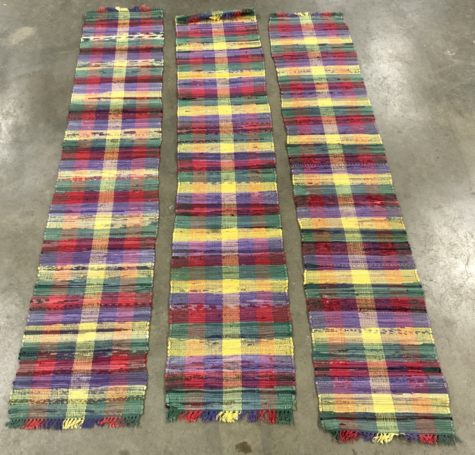 Lot 3 Multi Toned Fringes Hooked Runners: Runners are each hooked. Each have multi toned checkered detail. Edges of runners are fringed. Each piece appears to be vintage. Largest runner measures approximately 70 inches long 13.5 inches wide. 