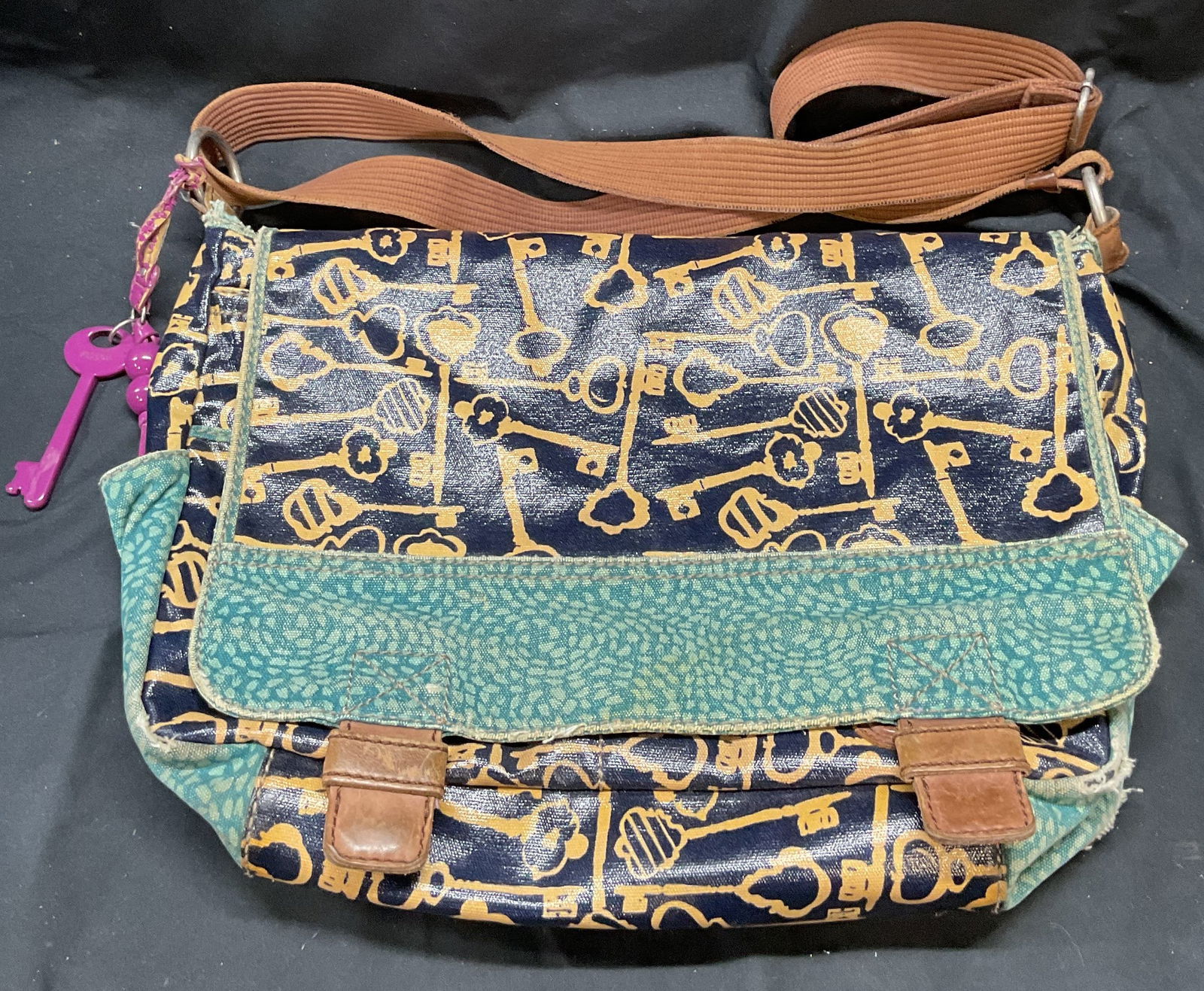 Fossil Key Per Blue Messenger Bag: Fossil Key Per Messenger bag in blue. Printed fabric and key design. Key motif keychain. Signed on interior. Measures approx. 14 x 3 x 10 inches. Wear to material including blemishes, fading, and tear
