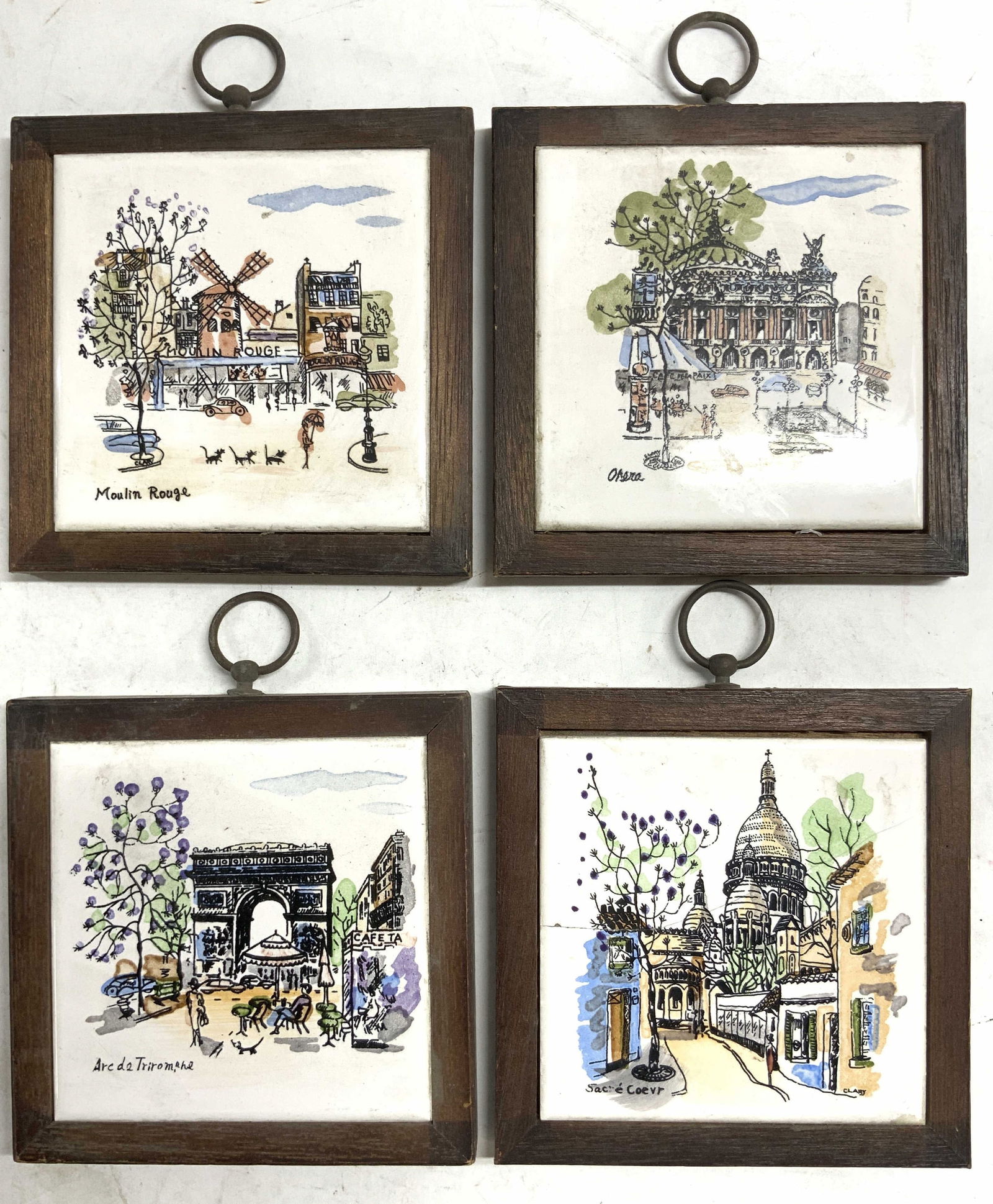 Set 4 Porc Tile Trivet Wall Hangings: Lot includes 4 trivets. Each are porcelain with brown toned wooden frames. Each have metal loops at top to hang on wall. Includes depictions of Moulin Rouge, Arc De Triomphe, Sacre Coevr & Opera. Triv