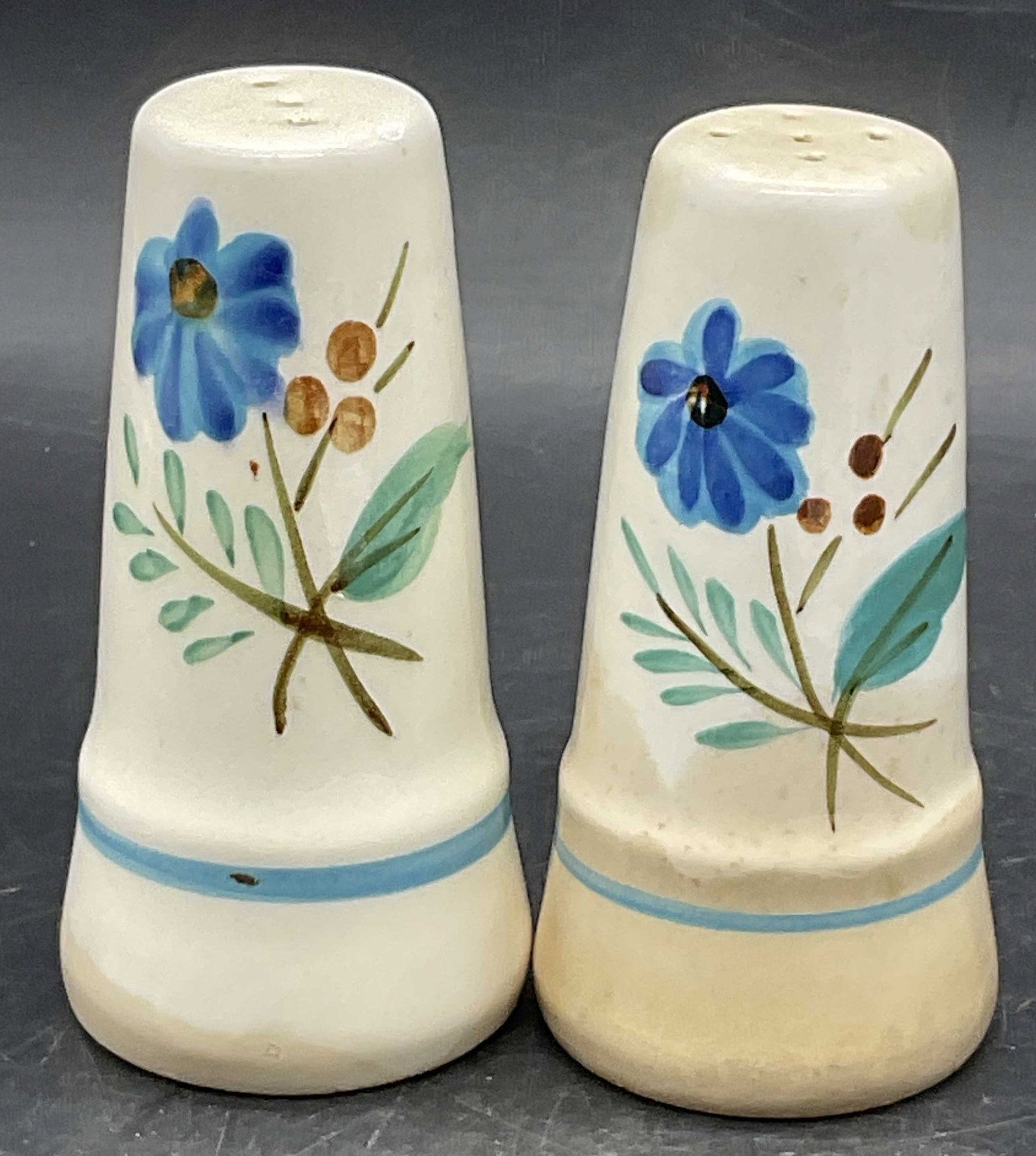 Pr STANGL Hand Paint Pottery Salt & Pepper Shakers: A pair of vintage hand painted pottery salt and pepper shakers. Floral motifs to the obverse. Undersides possess stoppers which read STANGL. Measures approx. 4H x 2W in. Discoloration, surface wear, a