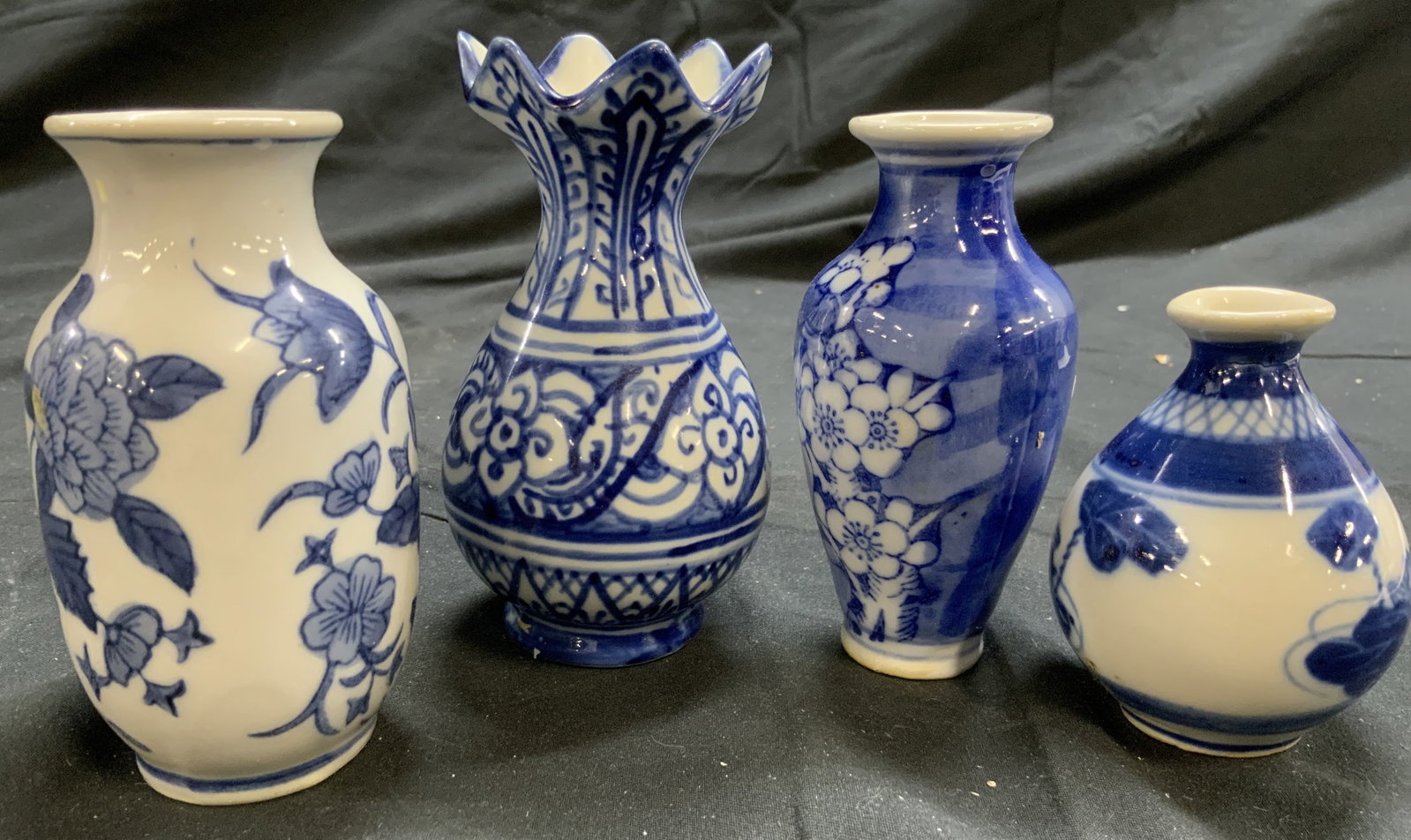 Lot 4 Asian Porcelain Chinoiserie Vases: Lot includes 4 vases. Each are white with blue toned detail. Each have various floral and leaf details. Vessels are each porcelain. One vase has pointed rim. Largest vase measures approximately 4.5 in