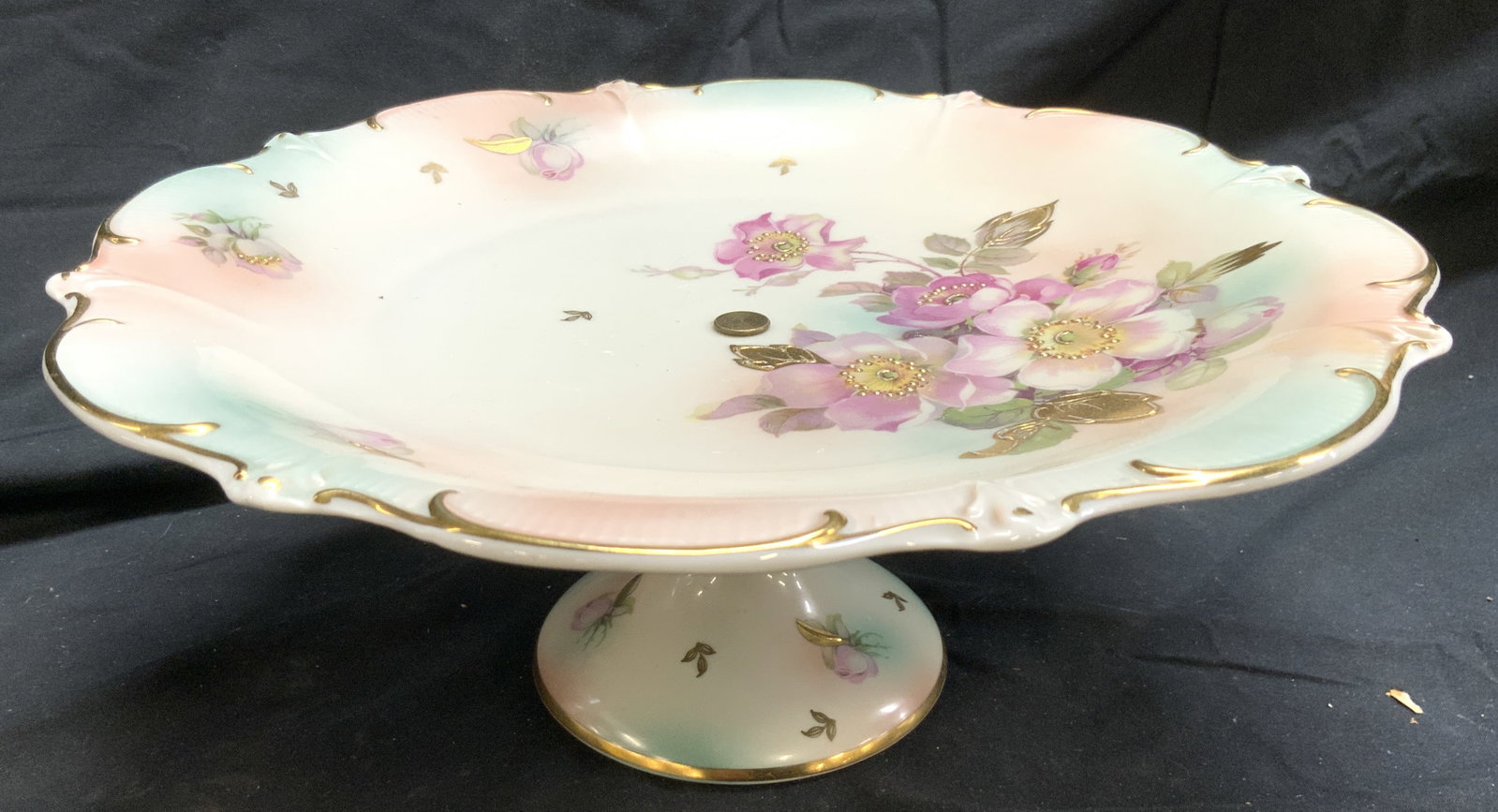 SCHUMANN ARZBERG German Porc Pedestaled Cake Plate: Underside is marked SCHUMANN ARZBERG GERMANY. Piece has light blue and pink cotton candy tones. Piece also has multi toned floral and leaf detail, & areas of gilt detail. Cake plate is pedestaled. Pie