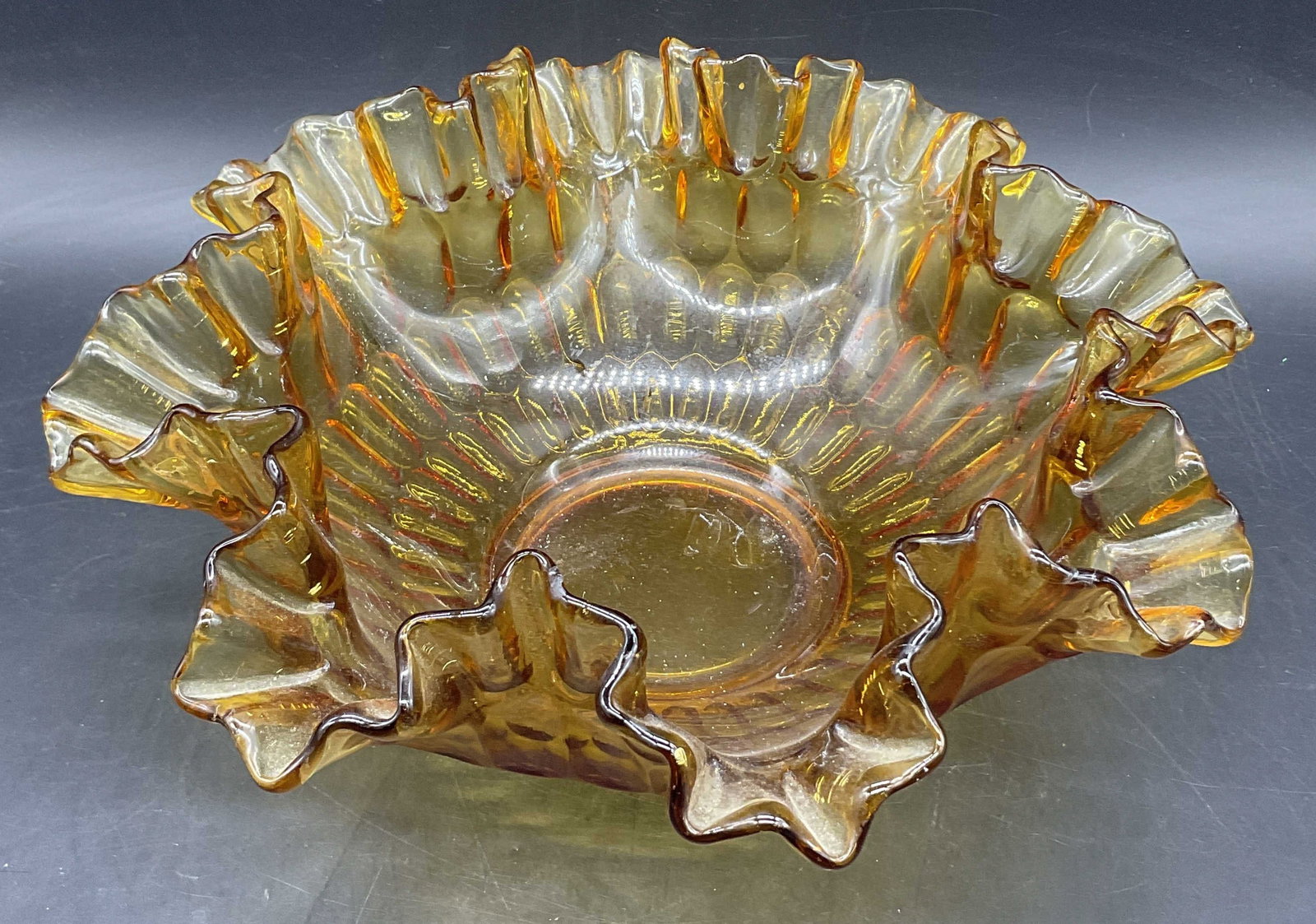 Thumbprint Colonial Amber Ruffle Rim Glass Bowl: Thumbprint Colonial Amber Ruffle Rim Glass Bowl. Thick walled and weighty. Measures approx. 4.5H x 10.25W in. Possibly Fenton, no apparent markings or inscriptions. Seam present. Surface wear consiste