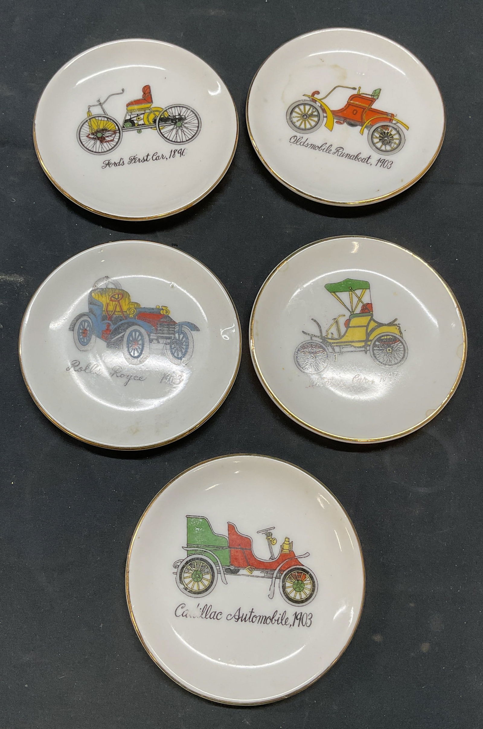 Set 5 Antique Car Motif Porcelain Plates: Set of 5 porcelain plates with hand painted antique car automobile motifs. Gilt rims. Measure approx 4 inches each. Loss to paint and scratching observed. Porcelain plate, display plate, decorative pl