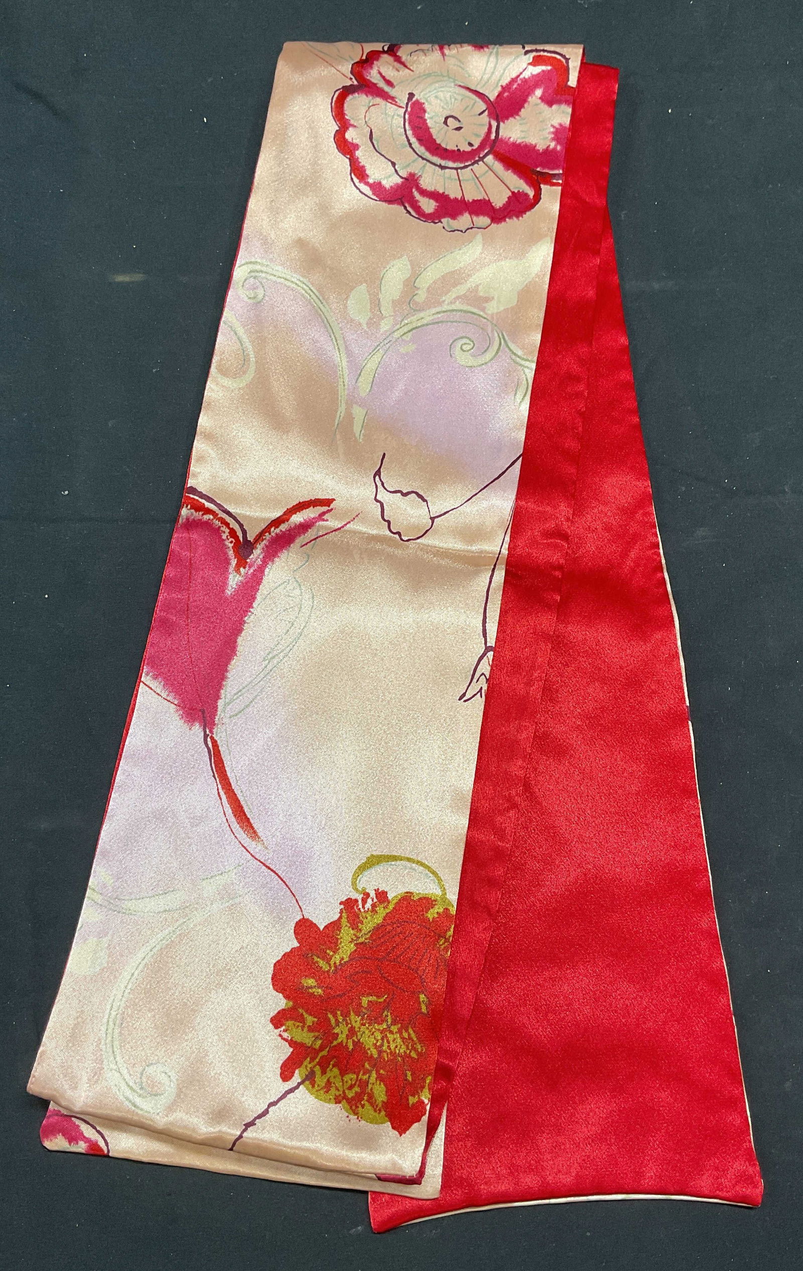 Red & Pink Floral Print Reversible Scarf: Red and pink reversible scarf. Floral print pink and solid red. Material feels like silk, possibly synthetic. Measures approx. 72 inches long. Some wear to material consistent with exposure. Pink scar